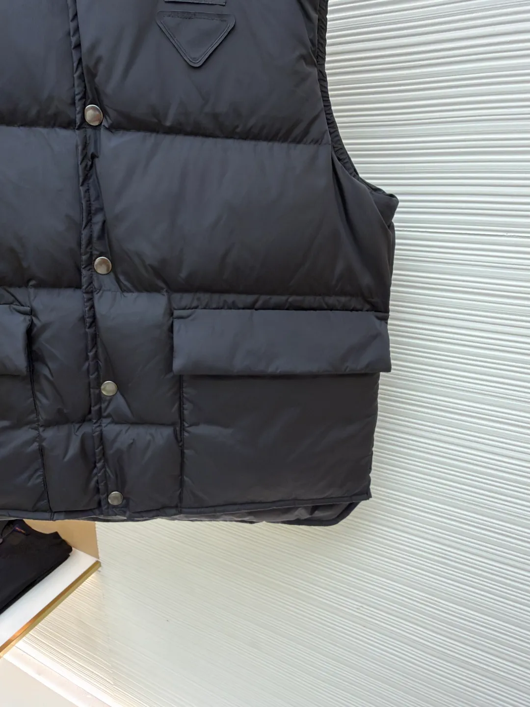 PRADA fabric triangle down vest ●Original version: purchased and developed by 12092 ●Item number: 1681119-C10 ●Fabric: white duck down fabric ●Technology: patch production ●Version: fitted version ●Weight: about 430 grams ●Size: 46-48-50-52 ●Description: The brand's iconic regenerated nylon fabric is selected, which has the same performance as traditional nylon, with high strength, tear resistance, wear resistance and other characteristics. It is lightweight and waterproof, suitable for various scenarios. Anti-wrinkle, quick-drying and easy to maintain on a daily basis. The felt cloth material is flatly fixed on the stamping machine table. Under the control of the ground controller, the upper mold is driven to move downward at extremely high speed and pressure. The sharp edge under pressure cuts off the felt cloth fibers instantly and cleanly like a paper knife. The whole process is completed within milliseconds. Through precise calculation, the triangle shape with no burrs and brushed edges is formed. It uses 90 white duck down with a weight of 160g to ensure excellent thermal insulation performance. After strict screening and processing, the velvet is not easy to drill, ensuring durability. The overall wiring is straight and delicate, the fabric is comfortable and soft, and the color is consistent without color difference. It can be matched with the same style to create a fashionable look and control various occasions. Customized accessories, complete with three standards, same style for men and women!