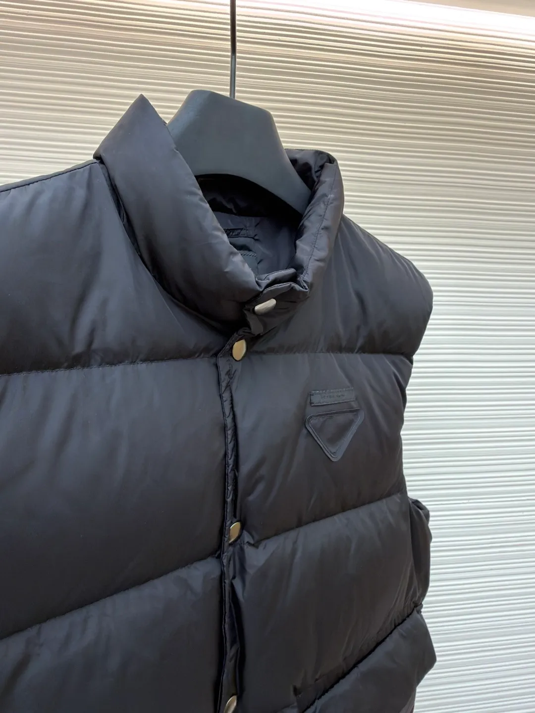 PRADA fabric triangle down vest ●Original version: purchased and developed by 12092 ●Item number: 1681119-C10 ●Fabric: white duck down fabric ●Technology: patch production ●Version: fitted version ●Weight: about 430 grams ●Size: 46-48-50-52 ●Description: The brand's iconic regenerated nylon fabric is selected, which has the same performance as traditional nylon, with high strength, tear resistance, wear resistance and other characteristics. It is lightweight and waterproof, suitable for various scenarios. Anti-wrinkle, quick-drying and easy to maintain on a daily basis. The felt cloth material is flatly fixed on the stamping machine table. Under the control of the ground controller, the upper mold is driven to move downward at extremely high speed and pressure. The sharp edge under pressure cuts off the felt cloth fibers instantly and cleanly like a paper knife. The whole process is completed within milliseconds. Through precise calculation, the triangle shape with no burrs and brushed edges is formed. It uses 90 white duck down with a weight of 160g to ensure excellent thermal insulation performance. After strict screening and processing, the velvet is not easy to drill, ensuring durability. The overall wiring is straight and delicate, the fabric is comfortable and soft, and the color is consistent without color difference. It can be matched with the same style to create a fashionable look and control various occasions. Customized accessories, complete with three standards, same style for men and women!