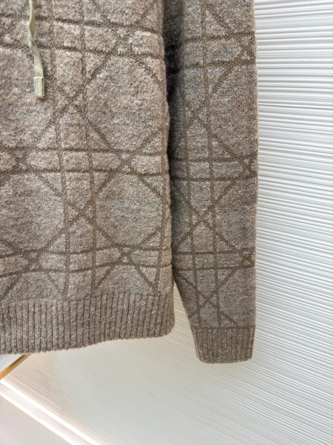 Dior diamond pattern jacquard knitted hoodie ●Original version: purchased and developed in 19726 ●Item number: 1681970-C70 ●Fabric: wool blended fabric ●Technology: jacquard knitting ●Color: camel ●Version: fitted version ●Weight: about 1315 grams ●Size: S-M-L-XL ●Description: This is LV The 2025 autumn and winter series of plush hooded sweaters are made of 100% Albaka wool blend, and the yarn contains 30% alpaca. It is woven with a 16-needle coarse weaving process. The surface presents a matte plush texture and is twice as warm as ordinary wool. The main body of the garment is made of rhombus plaid jacquard, with a three-dimensional texture formed by alternating front and back stitching techniques without additional seams. The hood is made of one-piece knitting, with an invisible shaping lining built into the brim, making it more comfortable to wear. The drawstring is made of core-spun rope of the same material, and the rope ends are treated with metal crimping, making it durable and not easy to wear. The finished product is ironed with low-temperature steam to avoid damage to the plush fibers. The cuffs and hem are ribbed for long-lasting elasticity and a good fit. The whole piece is sewn in an Italian workshop, with no exposed threads in the details, continuing the exquisite standards of the brand's high-end knitted items. The overall stitching is straight and delicate, the fabric is comfortable and soft, and the color is consistent with no color difference. It can be matched with the same style to create a fashionable look and control various occasions. Customized accessories, complete with three standards, the same style for men and women!
