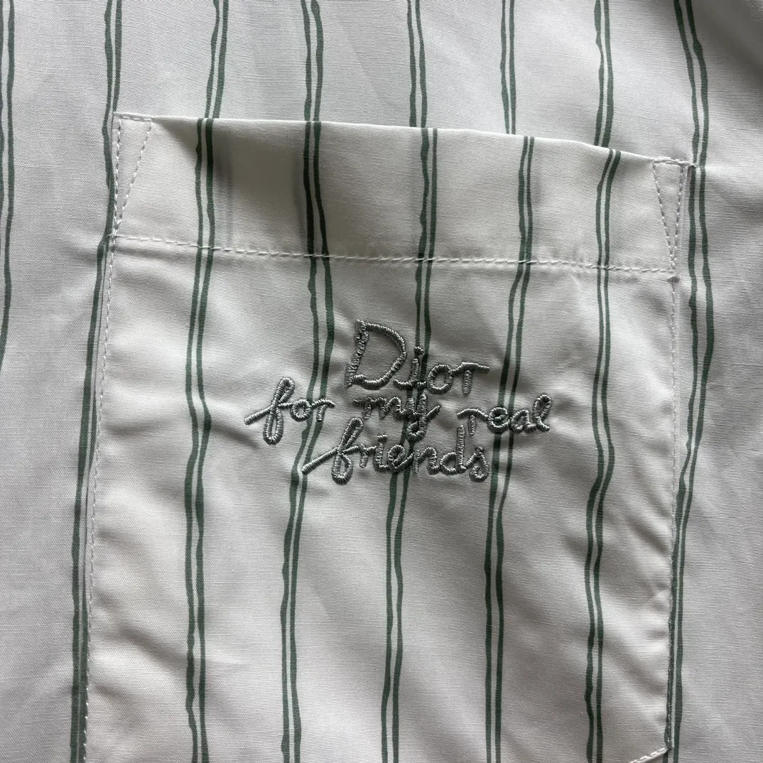 🅿️480 CD Blue and gray vertical pattern simple embroidered shirt Size: S-XL This shirt combines modern style with traditional beauty. Crafted from white cotton poplin, it features a blue and gray striped pattern displaying the Dior For My Real Friends signature from the DIOR AND HYLTON NE collection. A patch pocket on the chest and hidden button closure complete the design. Can be worn with everyday clothing.