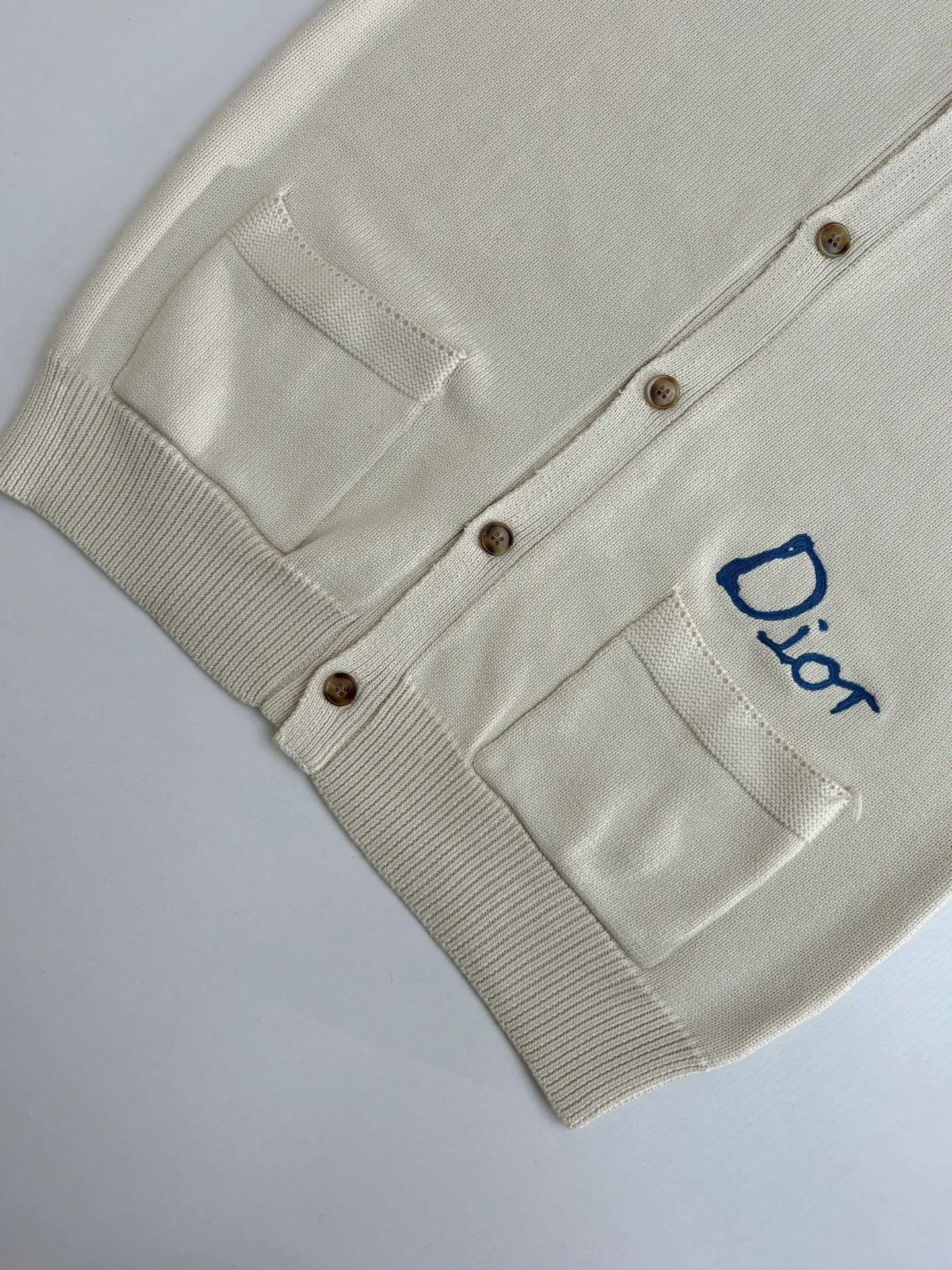 🅿️500 Dio*/Dior 25Fw new friend embroidered cotton blend button cardigan. The fabric is made of 40-count cotton yarn and wool, and the cotton content is 62%. It is mixed with 38% polyester. Mixing two kinds of wool materials can effectively make the upper body more three-dimensional. The embroidery uses high-density wool yarn embroidery technology, and the front numbers are all equipped with the joint series embroidery LOGO. The number of stitches is about 12,000. The auxiliary buttons are made of natural horn buttons, with the brand's iconic [DIOR] LOGO on the buttons. This cardigan displays the Dior For My Real Friends logo from the DIOR AND HYLTON NEL collaboration. Crafted from white cotton-blend jersey with embroidery on the front and back, button fastening and ribbed trims.  Size：S/M/L