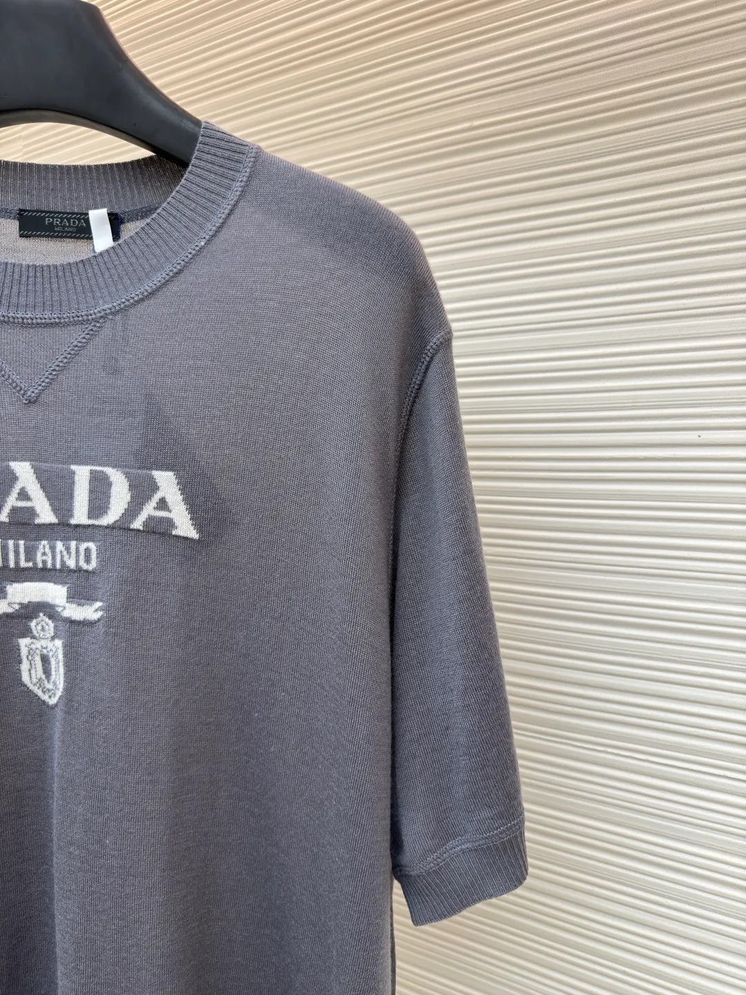 Prada classic LOGO jacquard wool round neck short sleeves ●Original version: purchased and developed by 11988 ●Item number: 1682515-A45 ●Fabric: wool fabric ●Technology: jacquard production ●Color: gray ●Version: fitted version ●Weight: about 150 grams ●Size: 46-48-50-52 ●Description: This PRADA gray knitted short-sleeve is woven with high-quality combed cotton threads. The body is made of vertical pit knitting technology. The texture is three-dimensional and elastic. It is soft and breathable when worn next to the skin. It has good drape and stiffness, and is not prone to pilling and deformation. The brand letters and badge pattern on the front of the garment are made with precision embroidery technology. The embroidery thread is made of imported high-gloss yarn. The stitches are dense and even, and the pattern is three-dimensional and clear. It forms a texture contrast with the knitted base to highlight the brand recognition. The neckline is a classic round neck design, with double-needle reinforced hemming technology and a customized threaded collar, which is durable and not easy to loosen. The cuffs and hem are ribbed in the same color. The overall cut is a loose silhouette. The stitching is straight and fine. The customized accessories and three standards are complete. The detailed craftsmanship shows the level of luxury. It is suitable for casual daily and light business wear scenarios. The overall wiring is straight and delicate, the fabric is comfortable and soft, and the color is consistent without color difference. It can be matched with the same style to create a fashionable look and control various occasions. Customized accessories, complete with three standards, same style for men and women!