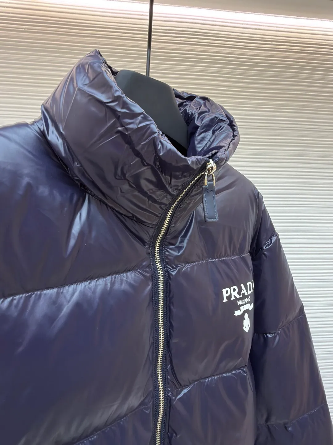 Prada Solid Color Logo Printed Quilted Stand Collar Jacket ●Original version: Purchased and developed for 8999 ●Item number: 1682008-E20 ●Fabric: white duck down fabric ●Technology: mechanical down filling ●Color: blue-purple ●Version: fitted version ●Weight: about 755 grams ●Size: S-M-L-XL ●Description: The fabric is made of high-gloss nylon, with a water-repellent treatment on the surface, making it smooth to the touch and protective. The interior is filled with high-fill down, and is divided into a full plaid pattern through even quilting to ensure warmth while avoiding accumulation of down. The neckline is a stand-up collar design, with a hidden metal zipper, and the zipper track is hemmed to make opening and closing smoother. The "PRADA" logo and brand logo on the left chest are made of precision offset printing technology, and the color is firm and not easy to fall off. The cuffs and hem are edged with elastic ribs, which fit the body shape and are highly windproof. The overall stitching is fine and neat, and the edges are overlocked in the same color, taking into account modern texture and high-end craftsmanship standards. The overall wiring is straight and delicate, the fabric is comfortable and soft, and the color is consistent without color difference. It can be matched with the same style to create a fashionable look and control various occasions. Customized accessories, complete with three standards, same style for men and women!