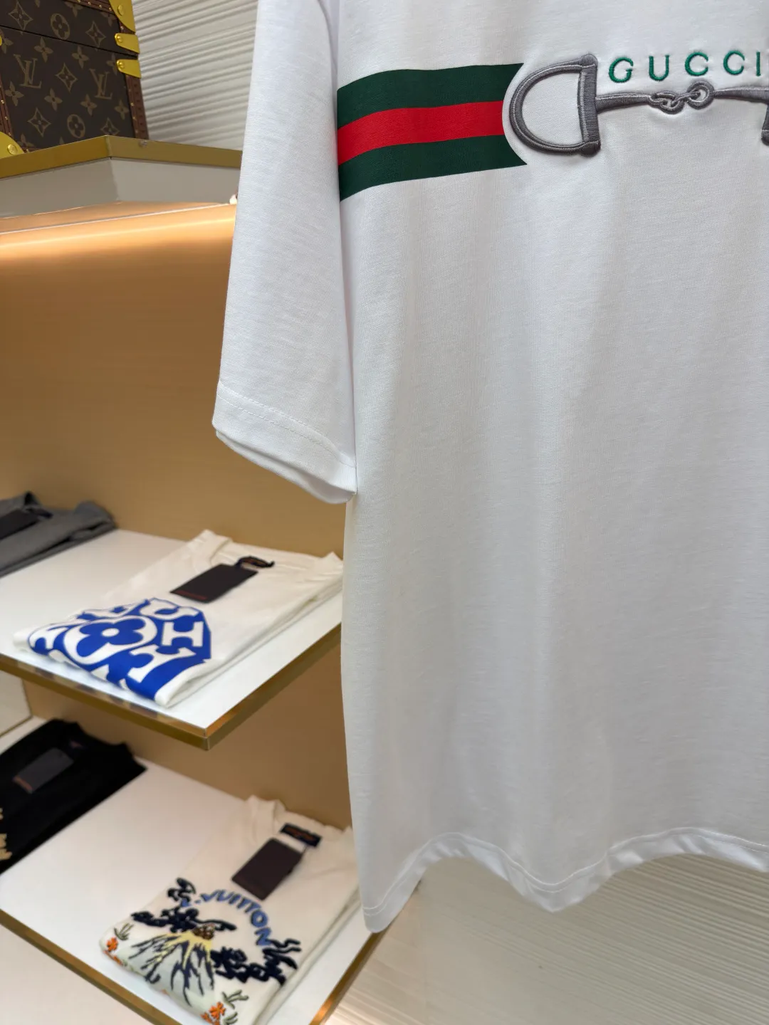 Gucci Lock Round Neck Short Sleeves ●Original version: Purchased and developed by 3031 ●Item number: 1682127-A05 ●Fabric: fine velvet knitted cotton fabric ●Technology: embroidery production ●Color: white ●Version: fitted version ●Weight: about 280 grams ●Size: XS-S-M-L ●Description: Made of 15S special woven compact cotton fine velvet knitted fabric with a weight of 230g/㎡; paired with 32S high count and high weight 1x1 rib, with a weight of 340g/㎡. Ribbing is used on the collar to ensure excellent elastic recovery and deformation resistance of the collar. The fabric uses compact spinning technology to effectively reduce yarn hairiness, making the fabric structure tighter, the surface smoother, and the pilling resistance better. The weight of 230g is medium to heavy, which gives the T-shirt good stiffness and drape, and is not easy to collapse, ensuring the texture of high-end ready-to-wear. The fine velvet knitted fabric has been lightly brushed or raised, giving it a softer, waxier skin-friendly feel than ordinary plain cotton. Environmentally friendly elastic glue printing uses water-based environmentally friendly slurry and polymer cross-linking technology to make the pattern have excellent elasticity and can expand and contract simultaneously with the fabric without cracking. The printing layer has a matte texture, is soft and smooth to the touch, and does not have the hardening feel of traditional offset printing, while maintaining the breathability of the fabric. It has strong color coverage, is washable and wear-resistant, and takes into account both visual performance and wearing comfort. Core-covered three-dimensional embroidery is made by pre-inserting a foam core material under the high-density embroidery layer as a filling base, and then fully covering it with embroidery threads. The process can create a three-dimensional pattern with highly pronounced convexities and rounded and full edges, and the visual effect is extremely impactful. The overall wiring is straight and delicate, the fabric is comfortable and soft, and the color is consistent without color difference. It can be matched with the same style to create a fashionable look and control various occasions. Customized accessories, complete with three standards, same style for men and women!