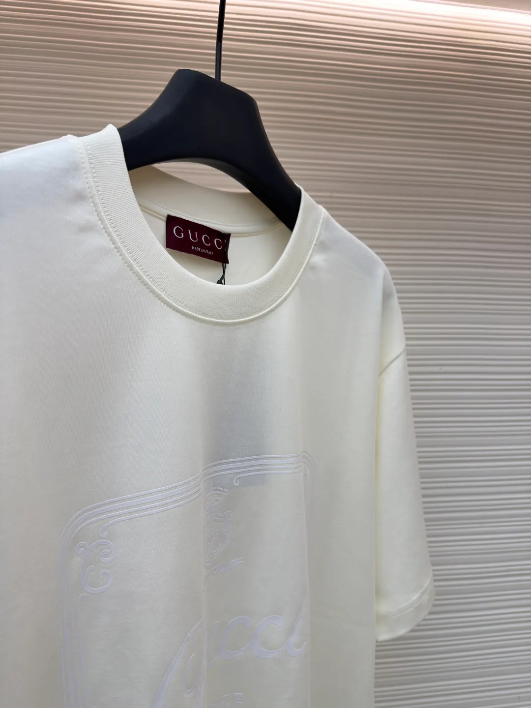 Gucci Buddha City printed round neck short sleeves ●Original version: purchased and developed by 5039 ●Item number: 1682280-A00 ●Fabric: soft knitted cotton fabric ●Technology: glue printing ●Color: apricot ●Version: fitted version ●Weight: about 245 grams ●Size: XS-S-M-L ●Description: This product is made of 60-count single-yarn double-sided knitted cotton with a weight of 170g/㎡; the neckline and other parts are matched with 32-count double-yarn ribbing. The high weight ensures a stable collar shape. 60 counts is an extremely high count, which means the yarn is extremely fine, which directly gives the fabric an extraordinary delicate, silky and soft touch. The front and back sides of the double-sided fabric have the same texture, which is uniform, thin and elastic. The weight of 170g is lightweight, ensuring the T-shirt is extremely light, breathable and drapey. It is almost invisible when worn and is very suitable for early spring. The color of the fabric is soft and high-end, which further enhances the exquisite texture of the fabric. The direct expression of the printing collection elements uses the environmentally friendly elastic thick plate bright glue printing process to place such a three-dimensional, bright, and highly present slogan printing on the simple sweater. This is a high-end special printing technology. Thick plate means that the slurry is accumulated thickly, which can form an obvious three-dimensional effect; after the bright slurry is cured, the surface will show a high-gloss glossy effect; the slurry itself is elastic and can stretch with the fabric. The special environmentally friendly elastic bright slurry is transferred through thick coating on the screen and then solidified at high temperature. Create a brand slogan pattern with significant 3D raised texture, mirror-like luster, and strong stretch resistance. To the touch, the pattern area has obvious stiff bulges and a smooth lacquered surface, which forms a strong contrast with the extremely soft fabric base and has a strong visual impact. The overall wiring is straight and delicate, the fabric is comfortable and soft, and the color is consistent without color difference. It can be matched with the same style to create a fashionable look and control various occasions. Customized accessories, complete with three standards, same style for men and women!