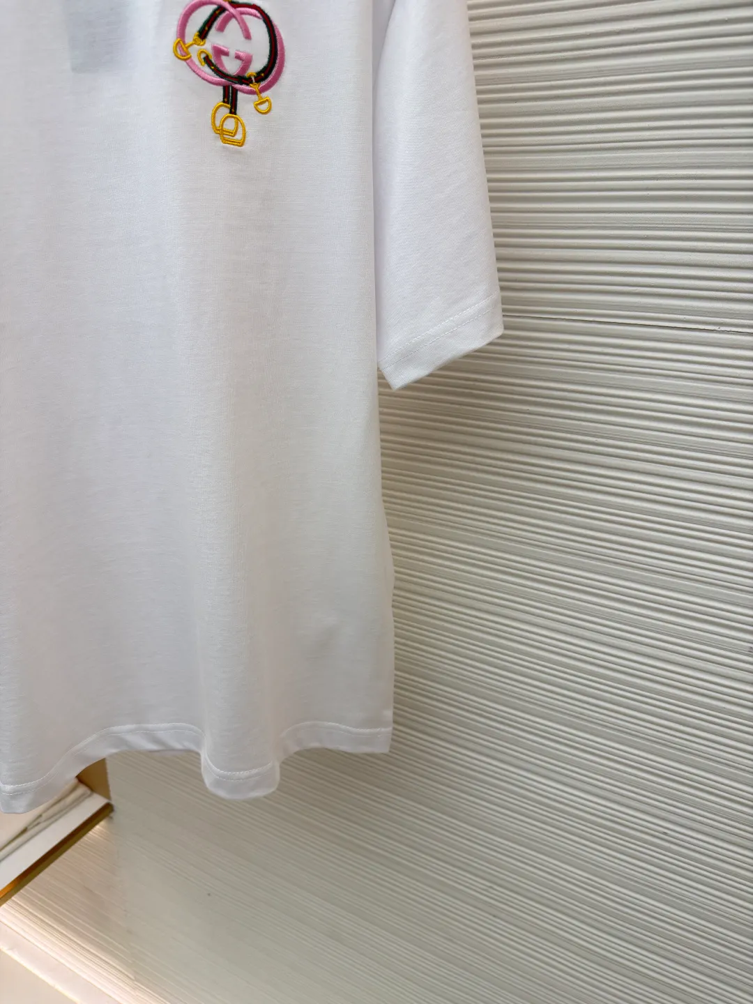 Gucci horseshoe buckle embroidered round neck short sleeves ●Item number: 1682116-A00 ●Material: fine velvet knitted cotton fabric ●Technology: embroidery production ●Color: white ●Version: fitted version ●Weight: about 270 grams ●Size: XS-S-M-L ●Description: Made of 15S special woven compact cotton fine velvet knitted fabric with a weight of 230g/㎡; paired with 32S high count and high weight 1x1 rib, with a weight of 340g/㎡. Ribbing is used on the collar to ensure excellent elastic recovery and deformation resistance of the collar. The fabric uses compact spinning technology to effectively reduce yarn hairiness, making the fabric structure tighter, the surface smoother, and the pilling resistance better. The weight of 230g is medium to heavy, which gives the T-shirt good stiffness and drape, and is not easy to collapse, ensuring the texture of high-end ready-to-wear. The fine velvet knitted fabric has been lightly brushed or raised, giving it a softer, waxier skin-friendly feel than ordinary plain cotton. Using multi-color fine flat embroidery technology, the pattern is completely covered and filled with extremely high-density stitches using embroidery threads of multiple colors according to the design artwork. Every detail and color transition of the complex pattern is accurately restored, so that the shape, light, shadow, and texture of the double-G interlocking webbing and stirrups are clearly presented. The final embroidery surface is flat, smooth, and full, with clear edges, and has a delicate effect and micro-three-dimensional effect similar to gongbi painting. The overall wiring is straight and delicate, the fabric is comfortable and soft, and the color is consistent without color difference. It can be matched with the same style to create a fashionable look and control various occasions. Customized accessories, complete with three standards, same style for men and women!