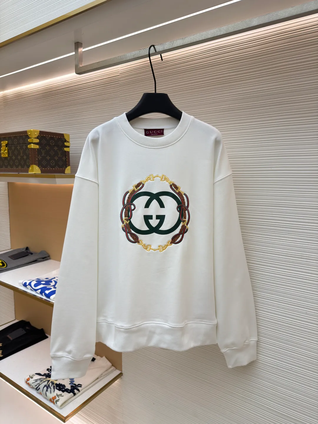 Gucci Bridle Web Round Neck Sweater ●Item No.: 1682279-A65 ●Material: 100% cotton ●Technology: Embroidery ●Color: White ●Version: Fitted ●Weight: about 645 grams ●Size: XS-S-M-L ●Description: This Gucci sweatshirt is made of high-weight combed cotton fabric. The fabric is tight and elastic, which can effectively maintain the stiffness and wearing comfort. The double G logo on the front adopts multi-layer embroidery technology, with gold thread to outline the outline, red and green velvet thread to fill the texture, and metallic chain stripe pattern appliqué. The stitches are fine and even, and each embroidery is precisely positioned to form a three-dimensional contrast with the fabric texture. The body is cut according to the loose shoulder design, and the shoulder line splicing adopts overlock stitching technology to reduce friction when wearing; the cuffs and hem are edged with ribs of the same color, which has long-lasting elasticity and is not easy to loosen. Sizes from XS to L are all standardized plate making, with increasing gradients in dimensions such as garment length and shoulder width. The stitching process uses a combination of flat seams and overlock seams to ensure the firmness of the garments and the exquisiteness of details. The overall craftsmanship combines the brand's iconic design with practical wearing performance. The overall wiring is straight and delicate, the fabric is comfortable and soft, and the color is consistent without color difference. It can be matched with the same style to create a fashionable look and control various occasions. Customized accessories, complete with three standards, same style for men and women!
