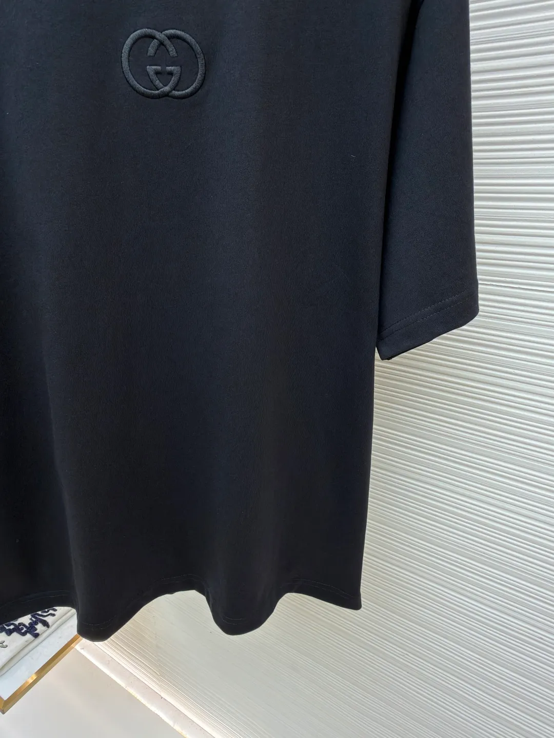 Gucci Double G embroidered round neck short sleeves ●Original version: purchased and developed by 2977 ●Item number: 1682217-A00 ●Fabric: fine velvet knitted cotton fabric ●Technology: embroidery production ●Color: black ●Version: fitted version ●Weight: about 280 grams ●Size: XS-S-M-L ●Description: Made of 15S special woven compact cotton fine velvet knitted fabric with a weight of 230g/㎡; paired with 32S high count and high weight 1x1 rib, with a weight of 340g/㎡. Ribbing is used on the collar to ensure excellent elastic recovery and deformation resistance of the collar. The fabric uses compact spinning technology to effectively reduce yarn hairiness, making the fabric structure tighter, the surface smoother, and the pilling resistance better. The weight of 230g is medium to heavy, which gives the T-shirt good stiffness and drape, and is not easy to collapse, ensuring the texture of high-end ready-to-wear. The fine velvet knitted fabric has been lightly brushed or raised, giving it a softer, waxier skin-friendly feel than ordinary plain cotton. Three-dimensional stitch embroidery is an embroidery process that uses high-density linear stitches to be closely arranged to form raised lines. The core is to use thicker embroidery thread, and the stitches are continuous and even without gaps. It naturally produces a raised height of 1-2 mm, making the edges of the pattern clear and sharp, and the touch feeling full and solid. The overall wiring is straight and delicate, the fabric is comfortable and soft, and the color is consistent without color difference. It can be matched with the same style to create a fashionable look and control various occasions. Customized accessories, complete with three standards, same style for men and women!