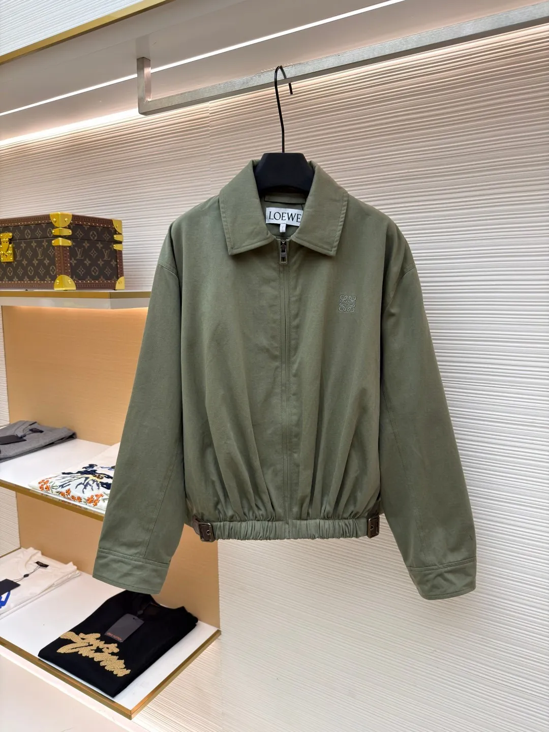 Loewe Army Green Trimmed Jacket ●Original version: Purchased and developed for 20900 ●Item number: 1682098-B40 ●Fabric: High weight dyed cotton satin fabric ●Technology: Leather patch production ●Color: Military green ●Version: Fitted version ●Weight: about 745 grams ●Size: 46-48-50-52 ●Description: Made of 100% pure cotton cloth, the fabric is dyed in the original color. The leather label is made of real cowhide composite, and the surface is stamped with gold powder to create the brand logo. The waist belt is made of multi-layer composite, and the oil edge design presents a different visual effect. Medium weight garment-dyed cotton satin jacket with gathered front and decorative contrasting belt. * Regular fit, standard length * Classic collar * Front zip closure, button cuffs * Seamed pockets, internal welt pockets * Fully lined * Anagram embroidery on chest, LOEWE embossed leather patch on back. The overall wiring is straight and delicate, the fabric is comfortable and soft, and the color is consistent without color difference. It can be matched with the same style to create a fashionable look and control various occasions. Customized accessories, complete with three standards, same style for men and women!