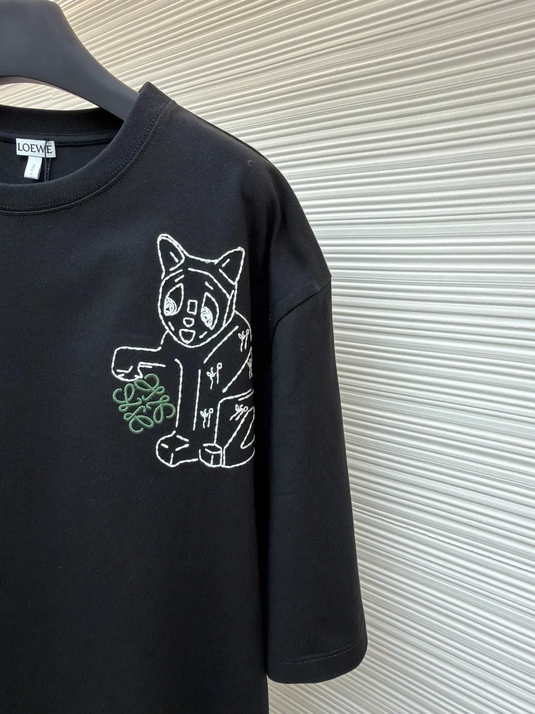Loewe Cat Line Pattern Round Neck Short Sleeve ●Original version: Purchased and developed at 4330 ●Item number: 1681867-A00 ●Material: combed cotton fabric ●Technology: embroidery production ●Color: black ●Version: fitted version ●Weight: about 295 grams ●Size: XS-S-M-L ●Description: Made of 15S fine cotton plain fabric, 230g; with 32S double yarn thread, 300g. Plain weave fabric made from combed cotton fibers has a more orderly arrangement and higher density than ordinary cotton, so it has better texture and luster. 15S fine cotton plain fabric is a high-quality cotton fabric with the characteristics of softness, comfort, good breathability, and good durability. Anagram Embroidery Lucky Cat: The rice grain line embroidery process uses special ultra-fine embroidery thread and high-density stitching to create a pattern outline as delicate and continuous as grains. Its core feature lies in the precise arrangement of ultra-fine stitches, which require 12-15 stitches per centimeter to form full lines, and the edges present a handmade micro-waving effect. The fabric achieves a stroke-like gradient of thickness and flow. The overall pattern is light, breathable and smooth to the touch. It looks like a line outline from a distance, but the texture of interwoven fibers can be seen up close. It is especially suitable for expressing delicate details such as logo outlines and geometric borders. Anagram embroidery: Using three-dimensional embroidery technology, the logo clearly restores the spacing curve. The mercerized embroidery thread with luster is selected, combined with complex embroidery needlework and fine detail processing to create a three-dimensional relief embroidery effect. Classic trademark letter design, fine embroidery and dense stitching, clear font and strong sense of lines and three-dimensionality. The overall wiring is straight and delicate, the fabric is comfortable and soft, and the color is consistent without color difference. It can be matched with the same style to create a fashionable look and control various occasions. Customized accessories, complete with three standards, same style for men and women!