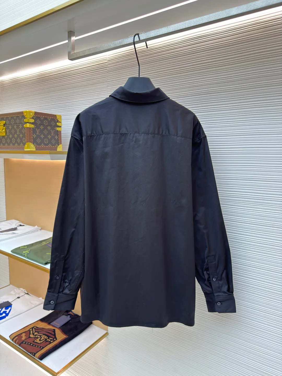 Loewe concealed logo lapel shirt ●Original version: Purchased and developed by 6454 ●Item number: 1680723-A75 ●Fabric: Light cotton poplin shirt fabric ●Technology: Printing ●Version: Fitted version ●Weight: about 290 grams ●Size: 36-38-40-42 ●Description: Poplin is a classic cotton fabric characterized by a large density difference between warp and weft yarns, forming a fine diamond-shaped grainy texture. This structure not only gives the fabric a refreshing and breathable wearing feel, but also ensures that its texture is light and thin but has a crisp texture, avoiding the shortcomings of ordinary thin cotton that easily collapses, perfectly supporting the neat silhouette of the shirt, while maintaining the unique skin-friendly comfort of cotton. The chest is decorated with a discharge printing process; discharge printing is a special process that erodes through the dyed base fabric to reveal the light-colored pattern of the original fabric. This makes the Anagram logo not simply covered on the fabric, but integrated with the fabric, feeling smooth and traceless, showing a low-key and high-end matte effect. Fit and design The shirt adopts a loose fit of standard length; it is precisely tailored to the pattern. It is neither too loose nor deliberately slim, aiming to create a clean silhouette and is extremely tolerant to all body types. The standard length ensures that the hem can be tucked into trousers or hang naturally, meeting a variety of wear needs, including formal and casual. The overall wiring is straight and delicate, the fabric is comfortable and soft, and the color is consistent without color difference. It can be matched with the same style to create a fashionable look and control various occasions. Customized accessories, complete with three standards, same style for men and women!