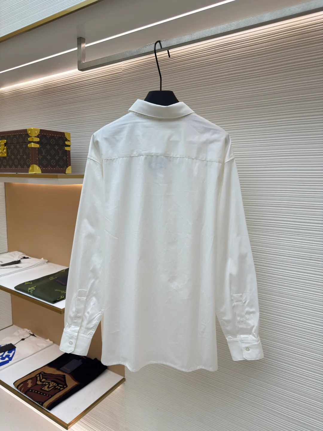 Loewe concealed logo lapel shirt ●Original version: Purchased and developed by 5268 ●Item No.: 1680722-A75 ●Fabric: Light cotton poplin shirt fabric ●Technology: Printing ●Version: Fitted version ●Weight: about 270 grams ●Size: 36-38-40-42 ●Description: Poplin is a classic cotton fabric characterized by a large density difference between warp and weft yarns, forming a fine diamond-shaped grainy texture. This structure not only gives the fabric a refreshing and breathable wearing feel, but also ensures that its texture is light and thin but has a crisp texture, avoiding the shortcomings of ordinary thin cotton that easily collapses, perfectly supporting the neat silhouette of the shirt, while maintaining the unique skin-friendly comfort of cotton. The chest is decorated with a discharge printing process; discharge printing is a special process that erodes through the dyed base fabric to reveal the light-colored pattern of the original fabric. This makes the Anagram logo not simply covered on the fabric, but integrated with the fabric, feeling smooth and traceless, showing a low-key and high-end matte effect. Fit and design The shirt adopts a loose fit of standard length; it is precisely tailored to the pattern. It is neither too loose nor deliberately slim, aiming to create a clean silhouette and is extremely tolerant to all body types. The standard length ensures that the hem can be tucked into trousers or hang naturally, meeting a variety of wear needs, including formal and casual. The overall wiring is straight and delicate, the fabric is comfortable and soft, and the color is consistent without color difference. It can be matched with the same style to create a fashionable look and control various occasions. Customized accessories, complete with three standards, same style for men and women!
