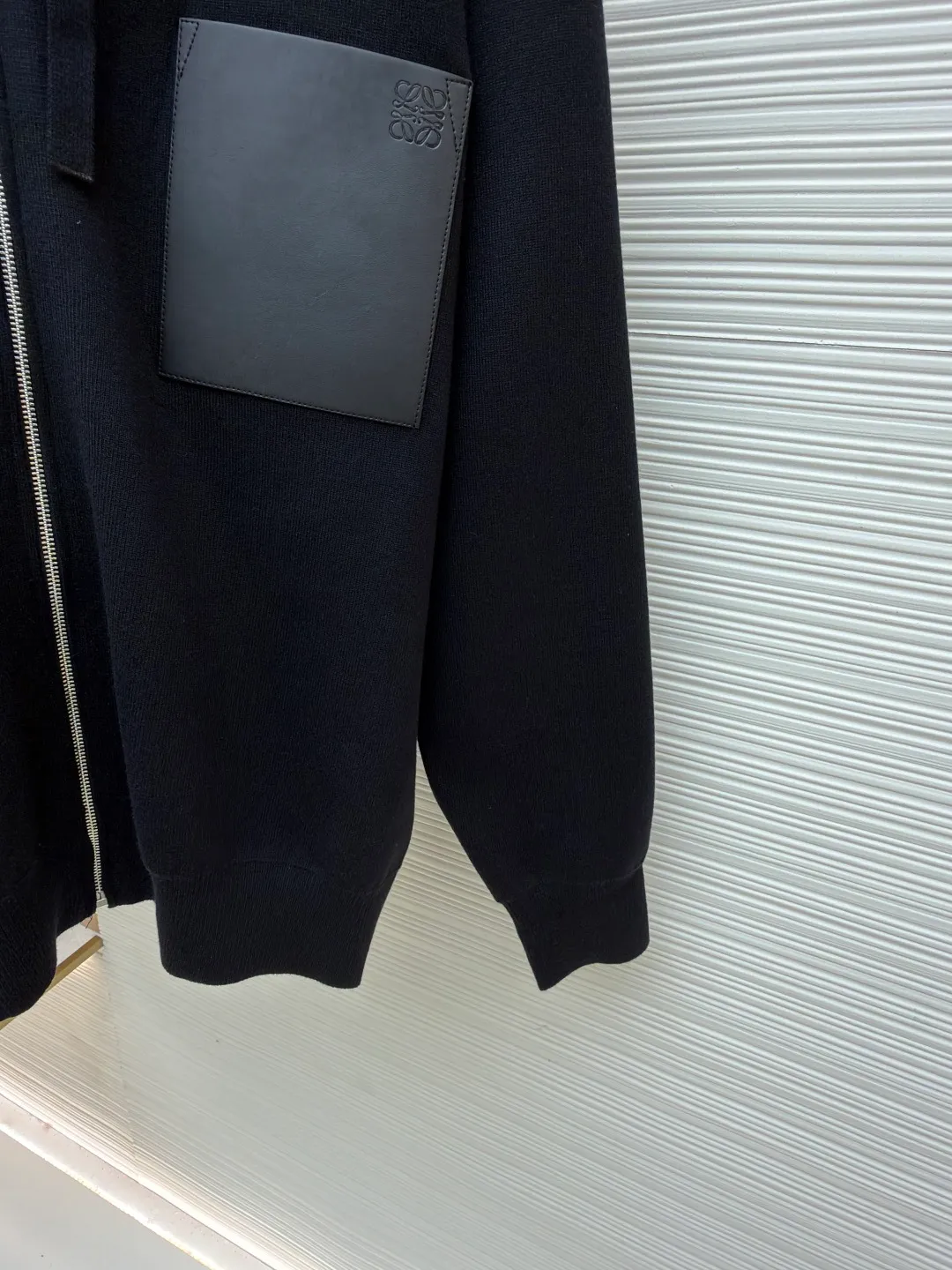 Loewe leather label pocket knitted zipper hoodie ●Original version: purchased and developed for 15900 ●Item number: 1681811-B15 ●Fabric: wool blended fabric ●Technology: knitted patch production ●Color: black ●Version: fitted version ●Weight: about 1025 grams ●Size: S-M-L-XL ●Description: Made of 55% merino wool and woven with a 14-needle imported machine. The entire garment weighs about 960-1000 grams. The upper body shape is very three-dimensional. The thermal insulation effect is also very good when worn outside. The leather label is made of double-layer composite imitation cowhide, and the process adopts three-dimensional relief embossing technology, and the Anagram icon is embossed with high temperature. Laser positioning and wiring, each piece of clothing passes multi-layer quality inspection before being shipped. The zippers are made of No. 5 bright white electroplated zippers, the LOEWE brand logo is electroplated and engraved on the sides, and the pull teeth are made of Euler electroplated teeth. Garment washing - removal of wool impurities - color fixation - fixed fit medium weight wool hooded sweatshirt. *Regular fit, standard length*Double side seams*Hooded collar*Leather chest patch pocket*Front zip closure*Ribbed cuffs and hem*Chest pocket trim. The overall wiring is straight and delicate, the fabric is comfortable and soft, and the color is consistent without color difference. It can be matched with the same style to create a fashionable look and control various occasions. Customized accessories, complete with three standards, same style for men and women!