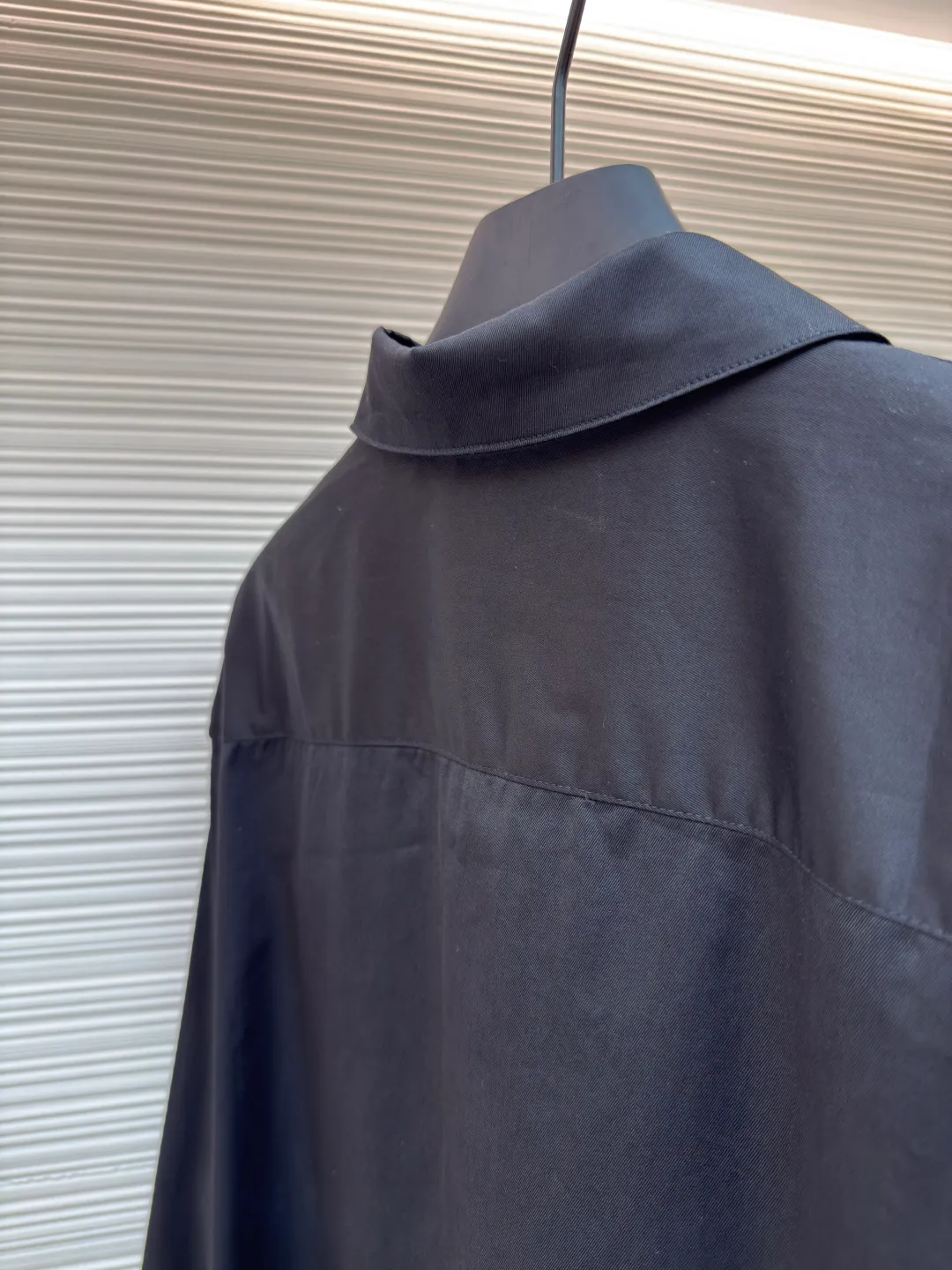 Loewe concealed logo lapel shirt ●Original version: Purchased and developed by 6454 ●Item number: 1680723-A75 ●Fabric: Light cotton poplin shirt fabric ●Technology: Printing ●Version: Fitted version ●Weight: about 290 grams ●Size: 36-38-40-42 ●Description: Poplin is a classic cotton fabric characterized by a large density difference between warp and weft yarns, forming a fine diamond-shaped grainy texture. This structure not only gives the fabric a refreshing and breathable wearing feel, but also ensures that its texture is light and thin but has a crisp texture, avoiding the shortcomings of ordinary thin cotton that easily collapses, perfectly supporting the neat silhouette of the shirt, while maintaining the unique skin-friendly comfort of cotton. The chest is decorated with a discharge printing process; discharge printing is a special process that erodes through the dyed base fabric to reveal the light-colored pattern of the original fabric. This makes the Anagram logo not simply covered on the fabric, but integrated with the fabric, feeling smooth and traceless, showing a low-key and high-end matte effect. Fit and design The shirt adopts a loose fit of standard length; it is precisely tailored to the pattern. It is neither too loose nor deliberately slim, aiming to create a clean silhouette and is extremely tolerant to all body types. The standard length ensures that the hem can be tucked into trousers or hang naturally, meeting a variety of wear needs, including formal and casual. The overall wiring is straight and delicate, the fabric is comfortable and soft, and the color is consistent without color difference. It can be matched with the same style to create a fashionable look and control various occasions. Customized accessories, complete with three standards, same style for men and women!
