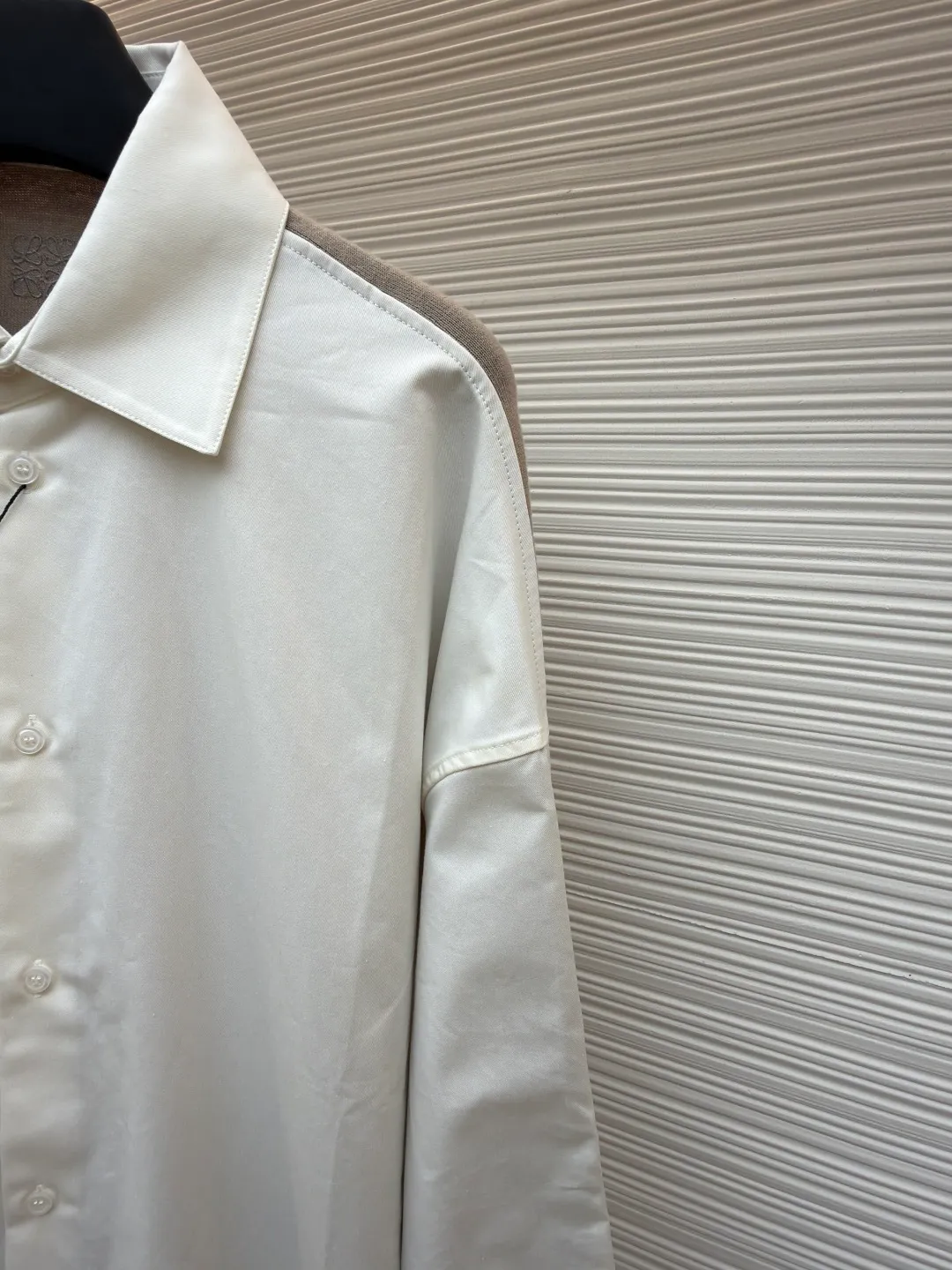 LOEWE cotton and knitted spliced shirt ●Original version: purchased and developed by 12479 ●Item number: 1680887-B50 ●Fabric: high-count cotton yarn fabric ●Technology: mechanical embroidery production ●Version: fitted version ●Weight: about 350 grams ●Size: 36-38-40-42 ●Description: The front panel is made of high-count cotton yarn through a weaving process with high warp density and low weft density to make a light and thin fabric with excellent breathability. The surface is smooth and flat, and feels as smooth as silk. At the same time, it retains the natural skin-friendly properties of cotton, making it snug and comfortable without any strange feeling. Because the warp yarns are closely arranged, the surface of the fabric shows longitudinal texture and soft luster, enhancing the visual sense of luxury. The back panel is woven with extremely fine wool yarn through high-count spinning technology to make a fabric with moderate density. It feels soft and skin-friendly, and has a delicate velvet feel on the surface. Wool fiber has a natural hollow structure, which can lock in still air and form an excellent thermal insulation layer. Even if it is light and thin, it has a good thermal insulation effect. Under the back collar, the high-precision calculation system of the computerized embroidery machine controls the coordinated operation of the machine head, needle bar, and thread spool. The fabric frame moves accurately in the horizontal and vertical directions to form a stitch track. The upper and lower thread tensions are adjusted to ensure that the stitches are smooth and free of floating threads, forming anagram embroidery with an error of ±0.1mm. The overall wiring is straight and delicate, the fabric is comfortable and soft, and the color is consistent without color difference. It can be matched with the same style to create a fashionable look and control various occasions. Customized accessories, complete with three standards, same style for men and women!
