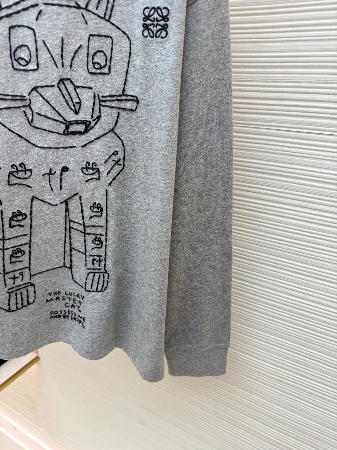 Loewe Stone Cat Round Neck Long Sleeve ●Original version: Purchased and developed by 5148 ●Item number: 1681939-A15 ●Fabric: Cotton jersey fabric ●Technology: Rice grain line embroidery production ●Color: gray ●Version: Fitted version ●Weight: about 250 grams ●Size: High-count combed cotton yarn eliminates most of the short hairiness through compact spinning process, making the yarn smoother and stronger. The woven fabric structure is extremely dense, flat and soft, with excellent anti-pilling ability and durability, while retaining the natural advantages of pure cotton, which is breathable and skin-friendly. The neckline is made of 32S 1x1 rib with a weight of 300g. The finer yarn count creates a more delicate and tight thread, which provides better resilience and anti-deformation than ordinary ribs, ensuring that the neckline can still remain stiff after being put on and taken off many times. The rice grain line embroidery process uses special ultra-fine embroidery thread and high-density stitching to create a pattern outline as delicate and continuous as grains. Its core feature lies in the precise arrangement of ultra-fine stitches, which require 12-15 stitches per centimeter to form full lines, and the edges present a handmade micro-waving effect. The fabric achieves a stroke-like gradient of thickness and flow. The overall pattern is light, breathable and smooth to the touch. It looks like a line outline from a distance, but the texture of interwoven fibers can be seen up close. It is especially suitable for expressing delicate details such as logo outlines and geometric borders. Anagram embroidery: Using three-dimensional embroidery technology, the logo clearly restores the spacing curve. The mercerized embroidery thread with luster is selected, combined with complex embroidery needlework and fine detail processing to create a three-dimensional relief embroidery effect. Classic trademark letter design, fine embroidery and dense stitching, clear font and strong sense of lines and three-dimensionality. The overall wiring is straight and delicate, the fabric is comfortable and soft, and the color is consistent without color difference. It can be matched with the same style to create a fashionable look and control various occasions. Customized accessories, complete with three standards, same style for men and women!