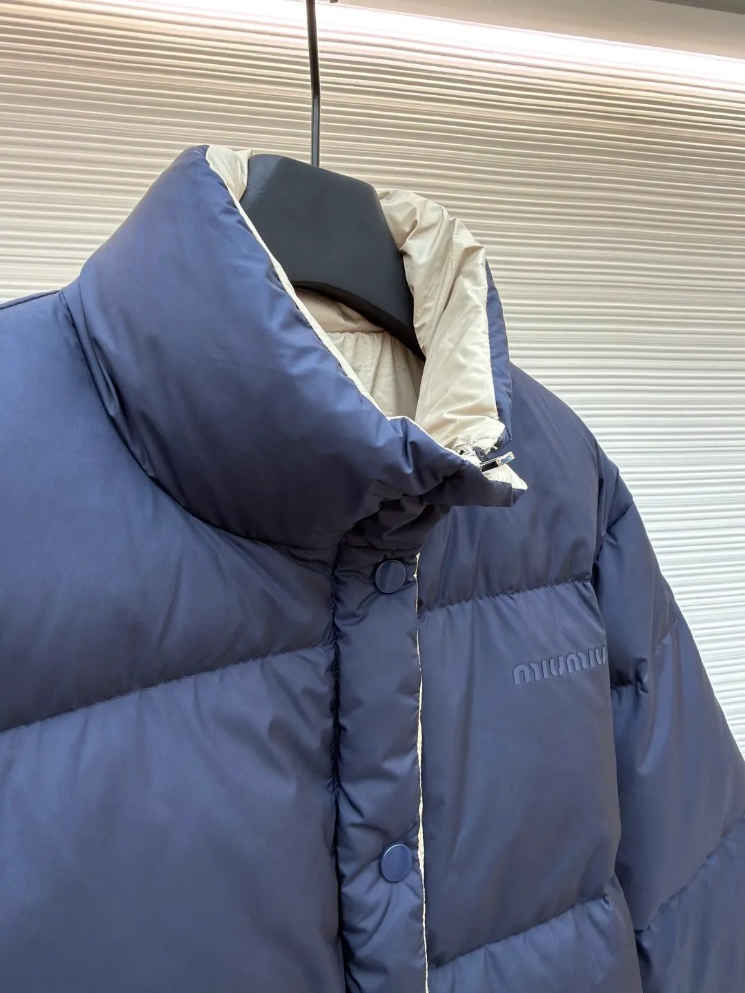 MIUMIU reversible stand collar down jacket ●Original version: purchased and developed by 21060 ●Item number: 1681385-D05 ●Fabric: white duck down fabric ●Technology: mechanical down filling ●Color: navy/khaki ●Version: fitted version ●Weight: about 675 grams ●Size: 36-38-40-42 ●Description: The filling is white duck down with 90% down content, which is one of the gold standards of down quality. "90% down content" means that the down content is extremely high and there are very few impurities such as feather stalks. The down tufts can capture more air and form an efficient thermal insulation layer, thus providing several times the loft and warmth of ordinary down while being lighter in weight. In the double-sided structure, ensuring that the down is evenly distributed between the two layers of fabric without clumping is the core challenge of the down filling process. The stand-up collar design not only improves the neatness of the shape, but also enhances the windproof and warm performance of the neck. Its internal structure needs to be stiff enough to maintain a three-dimensional shape, while at the same time ensuring the comfort of contact with the skin. The precision stitching in conjunction with the overall design not only plays a role in fixing the down and preventing displacement, but the uniformity, tension and pattern of the stitches have become important decorative elements, reflecting rigorous industrial aesthetics. The overall wiring is straight and delicate, the fabric is comfortable and soft, and the color is consistent without color difference. It can be matched with the same style to create a fashionable look and control various occasions. Customized accessories, complete with three standards, same style for men and women!