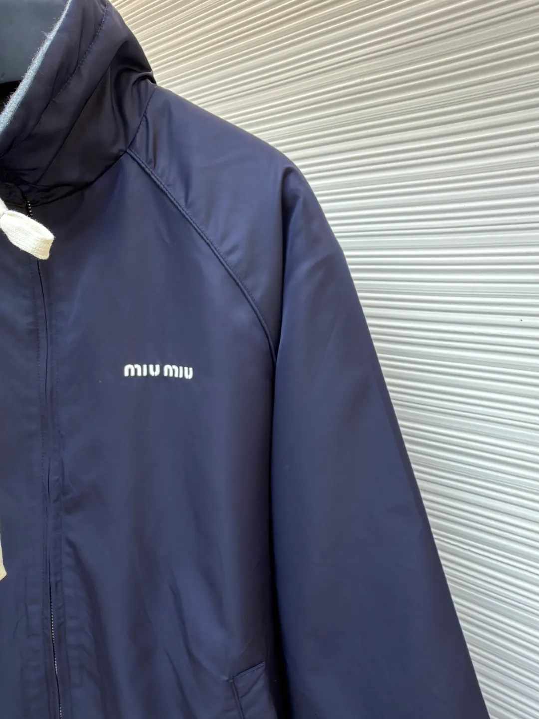 MIUMIU reversible technical fabric and fleece jacket ●Original version: 28200 purchase and development ●Item number: 1682256-C00 ●Fabric: wool blended anti-static plush fabric ●Technology: high temperature pre-shrunk production ●Color: blue/grey ●Version: fitted version ●Weight: about 890 grams ●Size: 36-38-40-42 ●Description: This Miu The Miu navy jacket is made of high-density polyester fabric, which has been treated with water-repellent treatment. The surface has a fine matte texture and has good windproof performance. The body is cut with raglan sleeves, and the three-dimensional patterning technology is used to make the shoulder lines more ergonomic, and there is no sense of restraint when moving. The neckline is spliced ​​with gray fleece lining, which is reinforced with double-needle hemming technology. The drawstring is made of natural cotton rope and has been brushed. The texture is soft and waxy and not easy to deform. The front is equipped with a customized metal zipper, and the smoothness of the gear rail has been tested multiple times. The zipper puller and brand logo are both made by laser engraving. The ribbed edges on the hem and cuffs are made of spandex blended material and are pre-shrunk to prevent them from loosening after long-term wear. The overall stitching uses dual processes of flat turning and overlocking. The stitching is even and fine, reaching the high standard of 12 stitches per inch, ensuring both a stiff silhouette and durability. The overall wiring is straight and delicate, the fabric is comfortable and soft, and the color is consistent without color difference. It can be matched with the same style to create a fashionable look and control various occasions. Customized accessories, complete with three standards, same style for men and women!