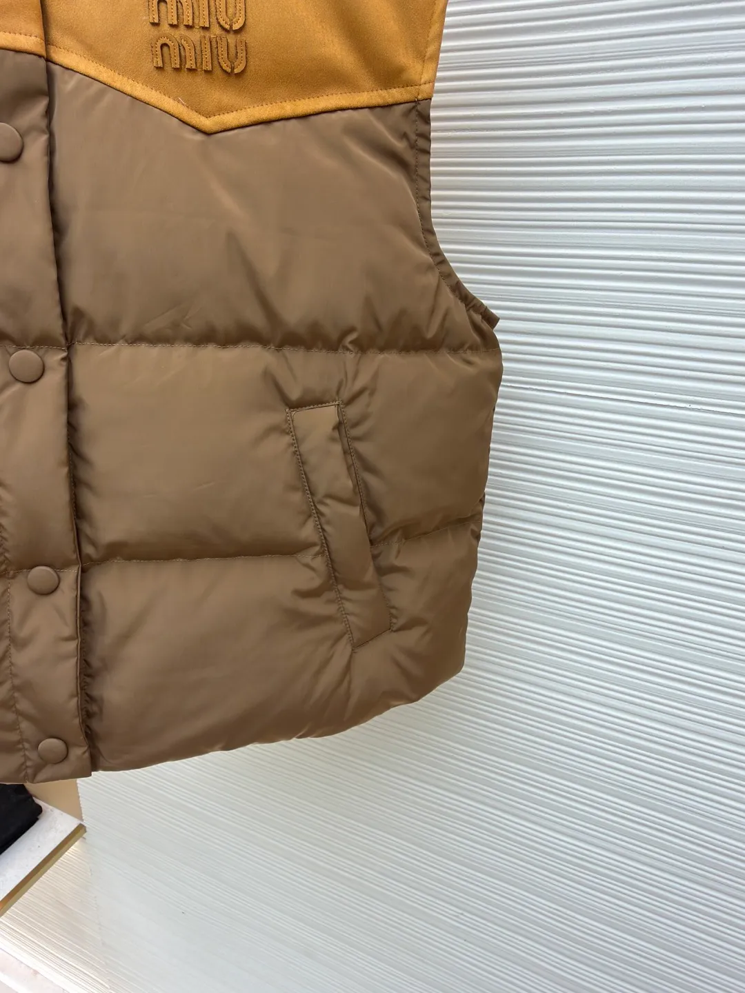MIUMIU flocked stitching lapel vest ●Original version: purchased and developed by 26615 ●Item number: 1681923-B50 ●Fabric: white duck down fabric ●Technology: embossed flocking production ●Color: brown ●Version: fitted version ●Weight: about 495 grams ●Size: S-M-L ●Description: This style is Miu Miu-style patchwork vest uses collision splicing technology: the main body is made of high-density matte nylon fabric, which is wind-resistant and anti-sand velvet; the collar and chest area are spliced with fine suede, and the texture contrast is enhanced by diagonal stitching. The filling is made of high-fill white duck down, and the segmented down filling process ensures an even amount of down in each grid, with a fill power of 600+; the placket is designed with metal snaps and a built-in concealed buckle for double temperature locking. The "MIU MIU" logo on the front chest adopts embossed flocking technology, which has a three-dimensional touch and is not easy to fall off; the cuffs and hem are elasticized to fit the body shape. The overall stitching uses anti-drilling velvet hemming needles, and the pockets are obliquely inserted invisible pockets, taking into account both beauty and practicality. It is a fashionable style that is lightweight and warm in autumn and winter. The overall wiring is straight and delicate, the fabric is comfortable and soft, and the color is consistent without color difference. It can be matched with the same style to create a fashionable look and control various occasions. Customized accessories, complete with three standards, same style for men and women!