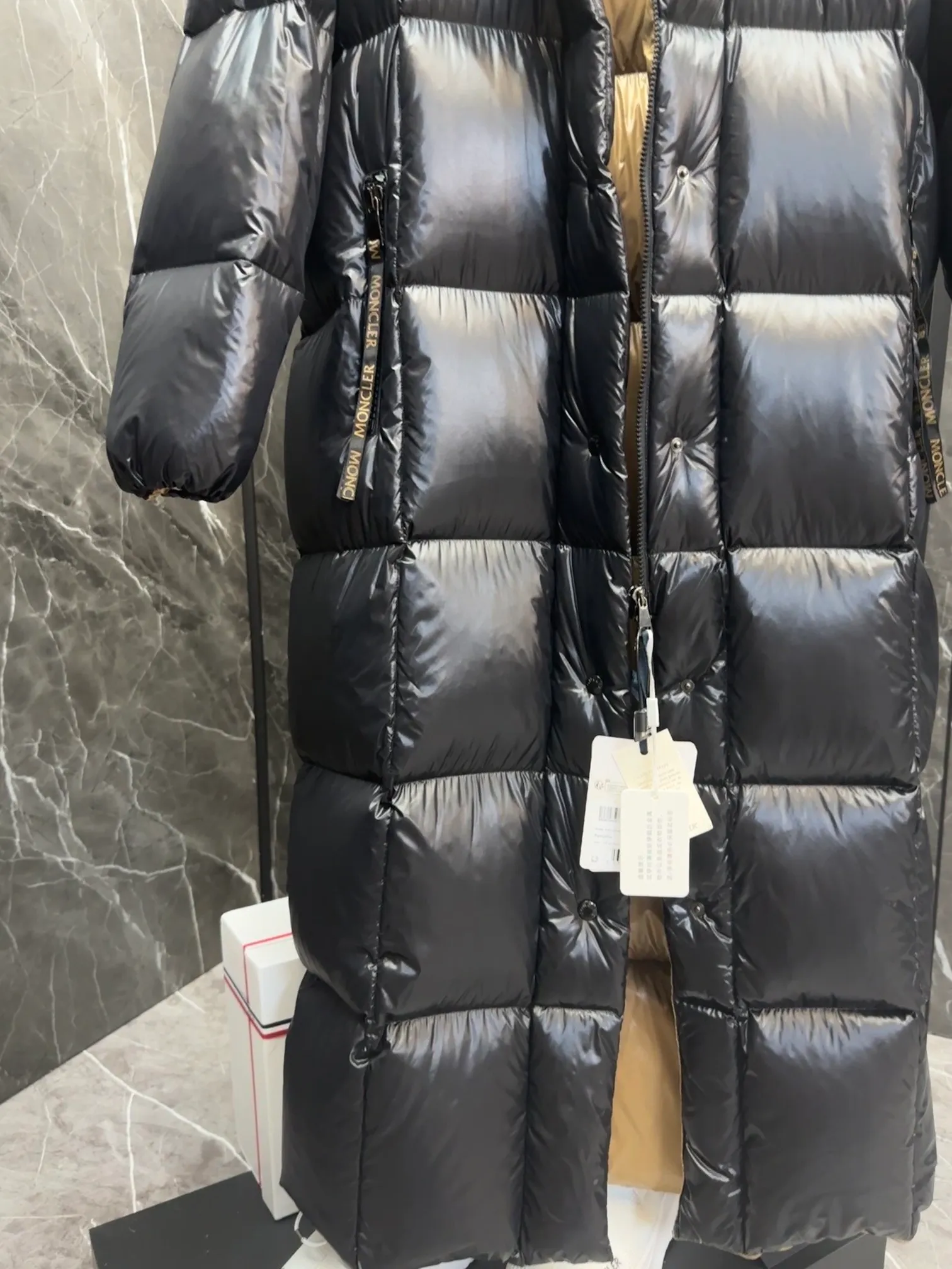 Special down  Parnaiba's long down jacket features graphic details and bold color blocking in signature patented nylon. The eye-catching design features large grille quilting and contrasting lining. The removable hood and adjustable hem make it easy to personalize the style, and the color-blocked pattern highlights the highly recognizable Moncler vibe. Details •Made from nylon laqué fabric •Contrast nylon laqué lining •Detachable hood with zipper and drawstring •Zip closure with black patented snap fastener ��Zip pocket Size: 0-4. Original runs large. D98108078950