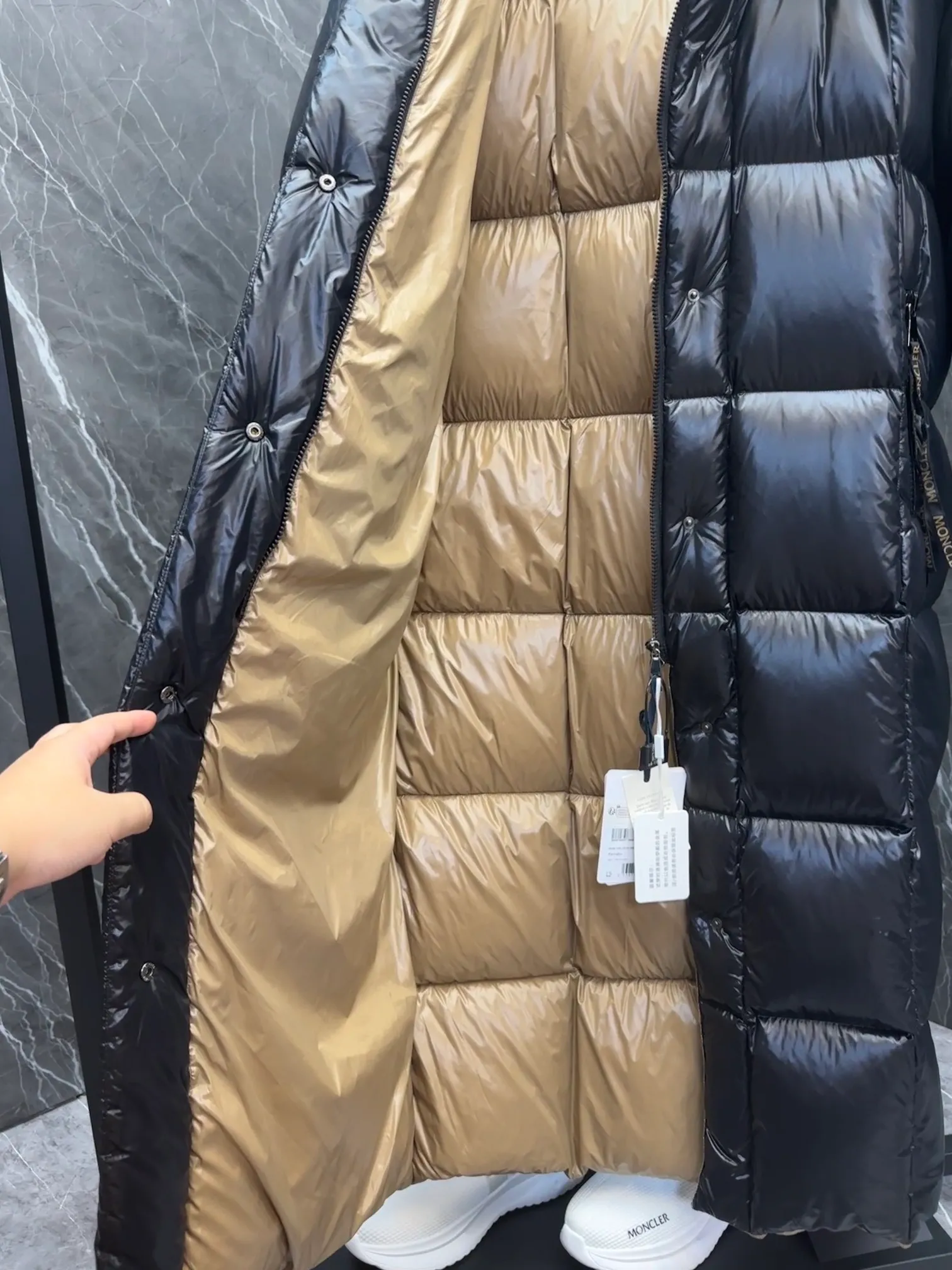 Special down  Parnaiba's long down jacket features graphic details and bold color blocking in signature patented nylon. The eye-catching design features large grille quilting and contrasting lining. The removable hood and adjustable hem make it easy to personalize the style, and the color-blocked pattern highlights the highly recognizable Moncler vibe. Details •Made from nylon laqué fabric •Contrast nylon laqué lining •Detachable hood with zipper and drawstring •Zip closure with black patented snap fastener ��Zip pocket Size: 0-4. Original runs large. D98108078950