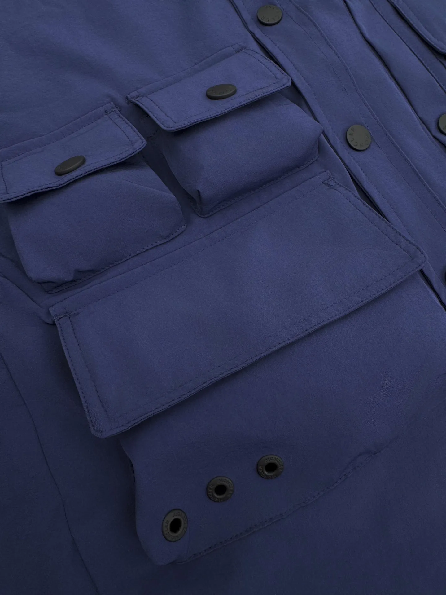 P610 Moncler Grenoble functional outdoor jacket Custom dyed double stretch mercerized poplin Custom dyed soft mesh pongee Excellent texture Comfortable and close to the skin Navy blue inspired by the deep sea Low-key statement of the contemporary gentleman Precision narrative of functional pocket system Balance of function and aesthetics The iconic Moncler logo appears on the sleeves for full recognition The triangular logo of the same color is hidden into the fabric texture like a mark in the undercurrent of the deep sea, extremely invisible and visible The detachable sleeve design allows for diversified outfits The style can be switched freely, chic and noble, taking into account the balance between outdoor practicality and urban aesthetics, leading the fashion. Process 1: Using three-in-one process, the glue is evenly coated on the surface of the substrate that needs to be composited, and then dried and solidified. Then the substrate coated with the adhesive film is laminated with the non-woven fabric, and then cooled and solidified, and then composited with the filter non-woven fabric. The workmanship is cumbersome and complex, time-consuming and labor-intensive. Process 2: Embossed composite technology through computer scanning. Ensure that the size and shape of the imprint are consistent with the original, then use special glue as an adhesive to combine and then solidify to achieve complete dryness and the best bonding effect. Process 3: Use CNC laser burning and cutting. Based on the high-energy characteristics of the laser, the moving path of the laser beam is precisely controlled by the laser generator to achieve precise cutting of the shape. Process 4: Template machine bag opening. The preset template guides the position, shape and size of the bag opening. The accuracy ensures the quality of the bag opening effect. Process 5: Uses infrared special machine to tack buttons. The position is more precise and firm. Accessories: Customized 1:1 Moncler snap button Customized 1:1 Moncler resin buckle Customized 1:1 Moncler logo stamp Customized 1:1 Moncler logo armband Customized 1:1 Moncler zipper rope ring Customized 1:1 Moncler zipper pull Customized 1:1 Moncler trademark Version: Loose version Function: Detachable sleeve splicing Style can be switched at will Size: 1 2 3 4