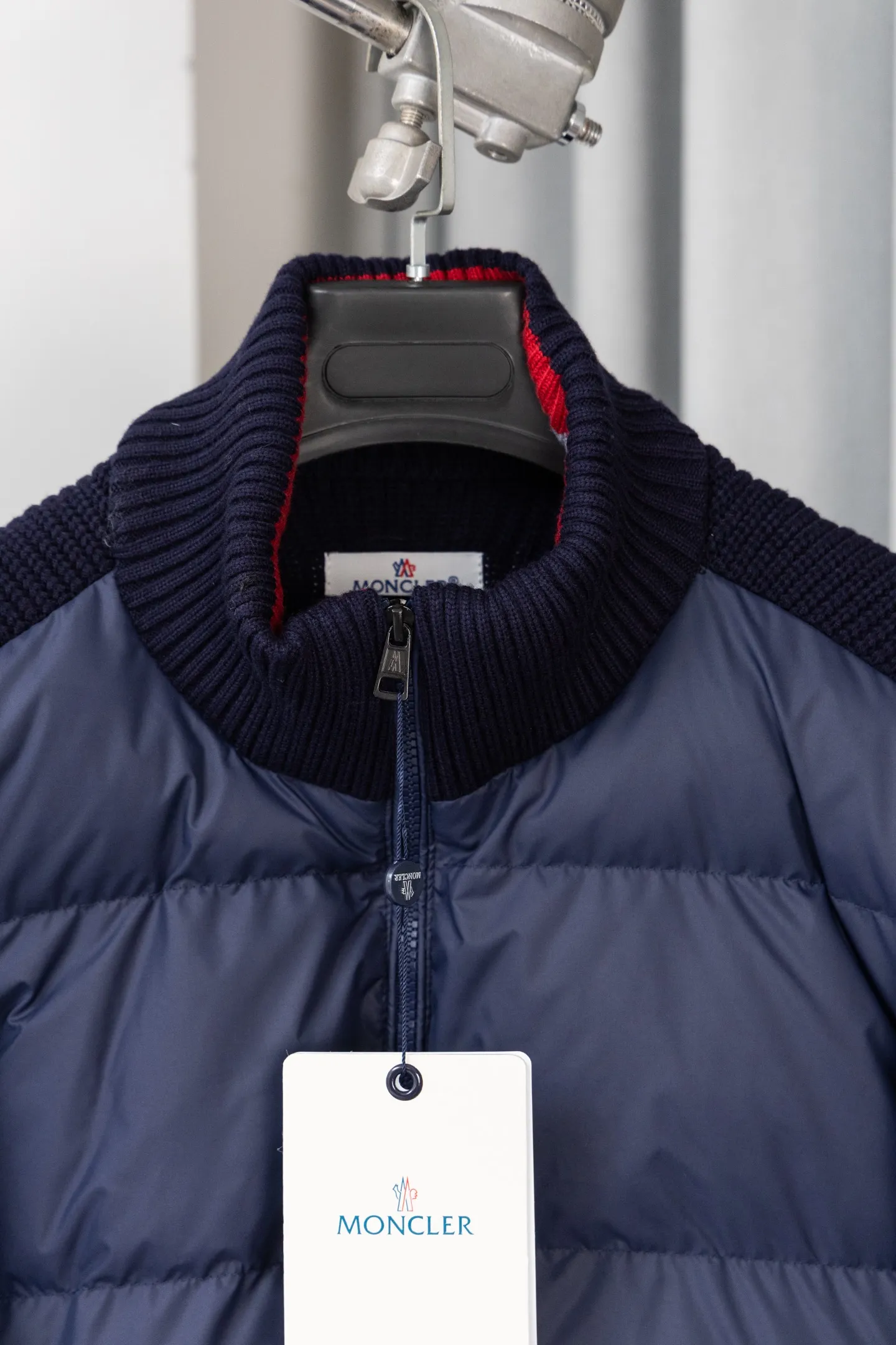 P560 Style number: M046 This is a knitted patchwork down jacket from Moncler. It combines the brand's high-end outdoor genes and fashion design. It is a luxurious item with both warmth and style in autumn and winter. Design highlights: Material splicing: Pure wool knitted sleeves are spliced ​​with a down front filled with 90 white duck down. The knitted part is soft and breathable, and the down part is fluffy and warm, achieving a dual fusion of style and function.  Detailed logo: The iconic Moncler badge pocket on the left arm is a classic embodiment of brand recognition; the stand-up collar design with a two-way zipper not only improves warmth, but also strengthens the neat styling.  Color embellishment: The contrasting red and blue stripes on the cuffs and hem inject vitality into the overall black tone, adding a retro college style charm. Craftsmanship and Quality: The down filling follows the European standard 90 down standard, with excellent fluffiness and down filling, with almost no stiff feeling. At the same time, it adopts the "line first and then separate down filling" process. The four-layer liner effectively prevents down from being drilled, and can maintain warmth even after long-term wear.  The knitted part is made of high-quality wool, which has a delicate touch and is not easily deformed. The splicing process with the down fabric is rigorous, showing a high-end texture level.  Style and Wearing This down jacket is based on the classic college style. The slim straight version can modify the body line and can be easily adapted to a variety of styles: it can be paired with jeans and casual shoes for a casual look on a daily basis. It can also be upgraded to an urban light luxury style by layering it with a turtleneck sweater inside and a suit outside. It is a key item in the winter wardrobe that is both practical and fashionable. Color: black, navy blue, sizes S-XL