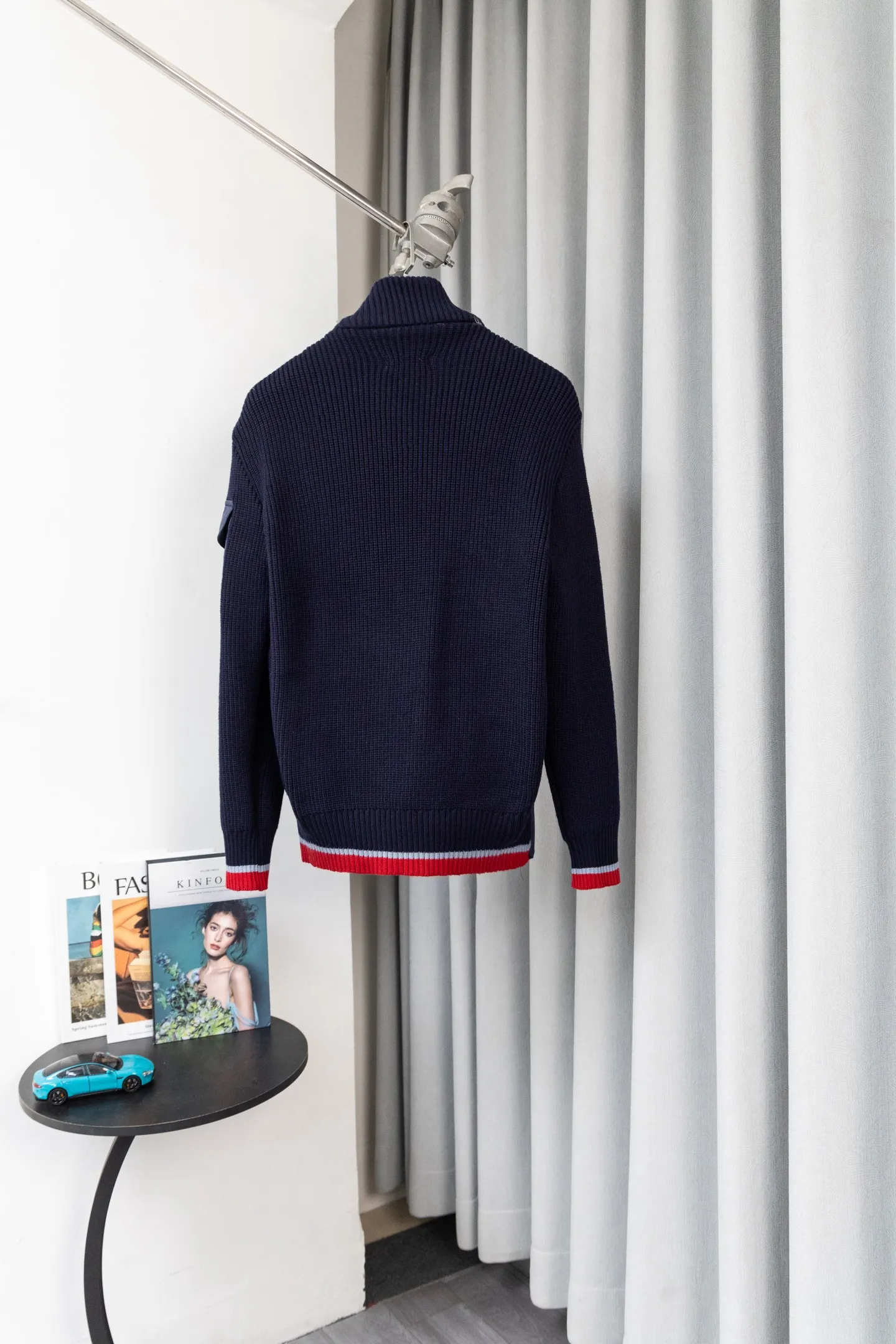 P560 Style number: M046 This is a knitted patchwork down jacket from Moncler. It combines the brand's high-end outdoor genes and fashion design. It is a luxurious item with both warmth and style in autumn and winter. Design highlights: Material splicing: Pure wool knitted sleeves are spliced ​​with a down front filled with 90 white duck down. The knitted part is soft and breathable, and the down part is fluffy and warm, achieving a dual fusion of style and function.  Detailed logo: The iconic Moncler badge pocket on the left arm is a classic embodiment of brand recognition; the stand-up collar design with a two-way zipper not only improves warmth, but also strengthens the neat styling.  Color embellishment: The contrasting red and blue stripes on the cuffs and hem inject vitality into the overall black tone, adding a retro college style charm. Craftsmanship and Quality: The down filling follows the European standard 90 down standard, with excellent fluffiness and down filling, with almost no stiff feeling. At the same time, it adopts the "line first and then separate down filling" process. The four-layer liner effectively prevents down from being drilled, and can maintain warmth even after long-term wear.  The knitted part is made of high-quality wool, which has a delicate touch and is not easily deformed. The splicing process with the down fabric is rigorous, showing a high-end texture level.  Style and Wearing This down jacket is based on the classic college style. The slim straight version can modify the body line and can be easily adapted to a variety of styles: it can be paired with jeans and casual shoes for a casual look on a daily basis. It can also be upgraded to an urban light luxury style by layering it with a turtleneck sweater inside and a suit outside. It is a key item in the winter wardrobe that is both practical and fashionable. Color: black, navy blue, sizes S-XL