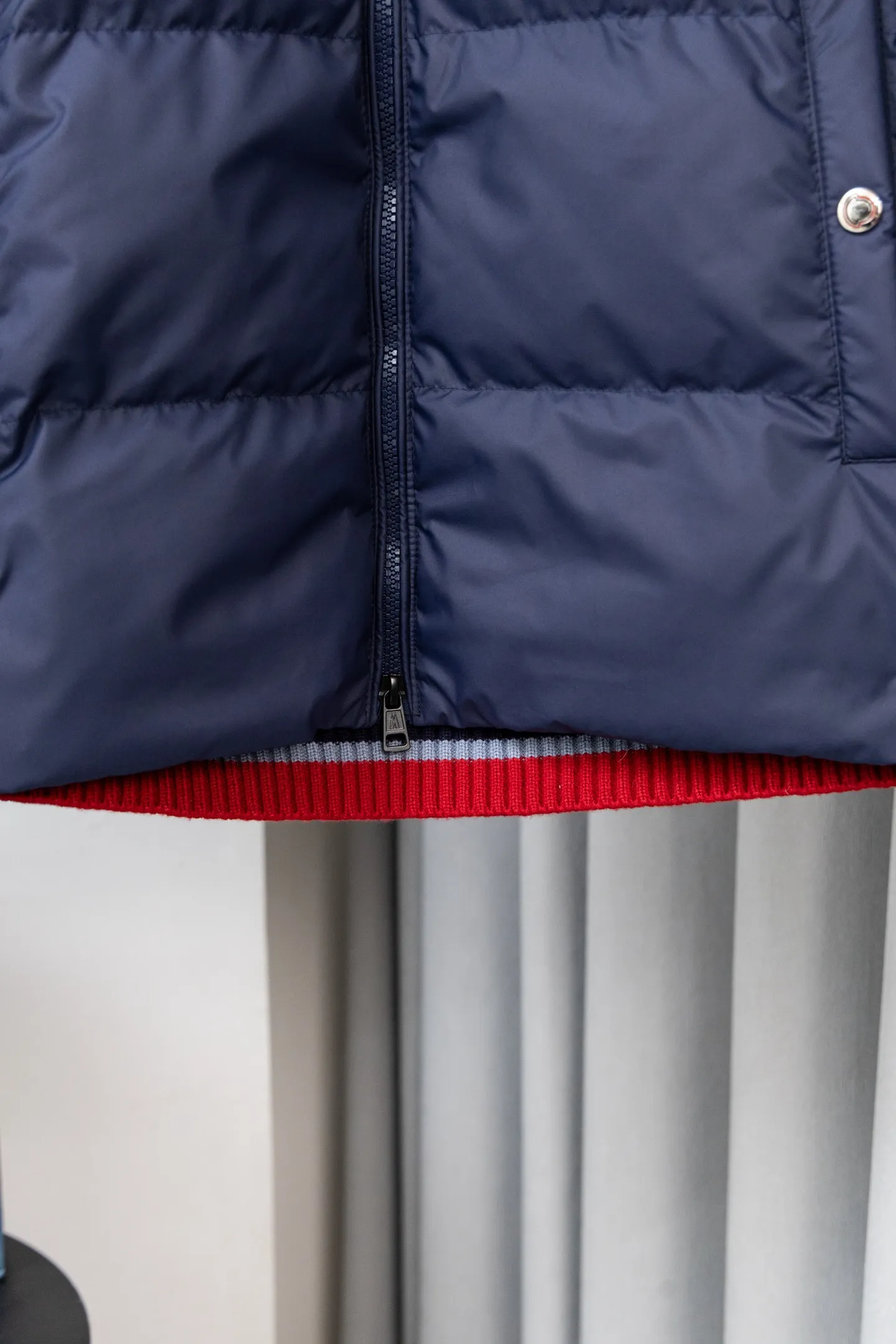 P560 Style number: M046 This is a knitted patchwork down jacket from Moncler. It combines the brand's high-end outdoor genes and fashion design. It is a luxurious item with both warmth and style in autumn and winter. Design highlights: Material splicing: Pure wool knitted sleeves are spliced ​​with a down front filled with 90 white duck down. The knitted part is soft and breathable, and the down part is fluffy and warm, achieving a dual fusion of style and function.  Detailed logo: The iconic Moncler badge pocket on the left arm is a classic embodiment of brand recognition; the stand-up collar design with a two-way zipper not only improves warmth, but also strengthens the neat styling.  Color embellishment: The contrasting red and blue stripes on the cuffs and hem inject vitality into the overall black tone, adding a retro college style charm. Craftsmanship and Quality: The down filling follows the European standard 90 down standard, with excellent fluffiness and down filling, with almost no stiff feeling. At the same time, it adopts the "line first and then separate down filling" process. The four-layer liner effectively prevents down from being drilled, and can maintain warmth even after long-term wear.  The knitted part is made of high-quality wool, which has a delicate touch and is not easily deformed. The splicing process with the down fabric is rigorous, showing a high-end texture level.  Style and Wearing This down jacket is based on the classic college style. The slim straight version can modify the body line and can be easily adapted to a variety of styles: it can be paired with jeans and casual shoes for a casual look on a daily basis. It can also be upgraded to an urban light luxury style by layering it with a turtleneck sweater inside and a suit outside. It is a key item in the winter wardrobe that is both practical and fashionable. Color: black, navy blue, sizes S-XL