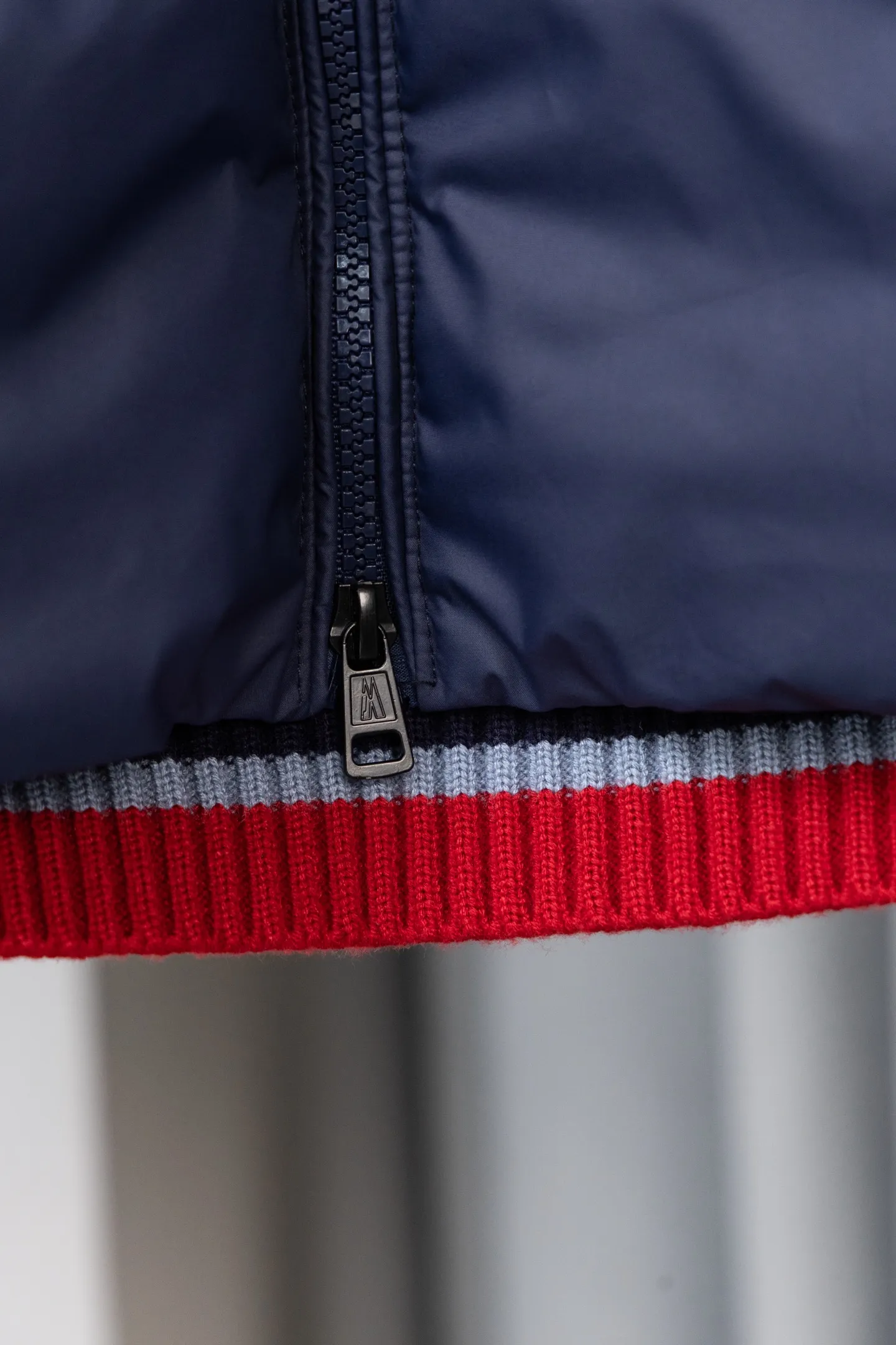 P560 Style number: M046 This is a knitted patchwork down jacket from Moncler. It combines the brand's high-end outdoor genes and fashion design. It is a luxurious item with both warmth and style in autumn and winter. Design highlights: Material splicing: Pure wool knitted sleeves are spliced ​​with a down front filled with 90 white duck down. The knitted part is soft and breathable, and the down part is fluffy and warm, achieving a dual fusion of style and function.  Detailed logo: The iconic Moncler badge pocket on the left arm is a classic embodiment of brand recognition; the stand-up collar design with a two-way zipper not only improves warmth, but also strengthens the neat styling.  Color embellishment: The contrasting red and blue stripes on the cuffs and hem inject vitality into the overall black tone, adding a retro college style charm. Craftsmanship and Quality: The down filling follows the European standard 90 down standard, with excellent fluffiness and down filling, with almost no stiff feeling. At the same time, it adopts the "line first and then separate down filling" process. The four-layer liner effectively prevents down from being drilled, and can maintain warmth even after long-term wear.  The knitted part is made of high-quality wool, which has a delicate touch and is not easily deformed. The splicing process with the down fabric is rigorous, showing a high-end texture level.  Style and Wearing This down jacket is based on the classic college style. The slim straight version can modify the body line and can be easily adapted to a variety of styles: it can be paired with jeans and casual shoes for a casual look on a daily basis. It can also be upgraded to an urban light luxury style by layering it with a turtleneck sweater inside and a suit outside. It is a key item in the winter wardrobe that is both practical and fashionable. Color: black, navy blue, sizes S-XL