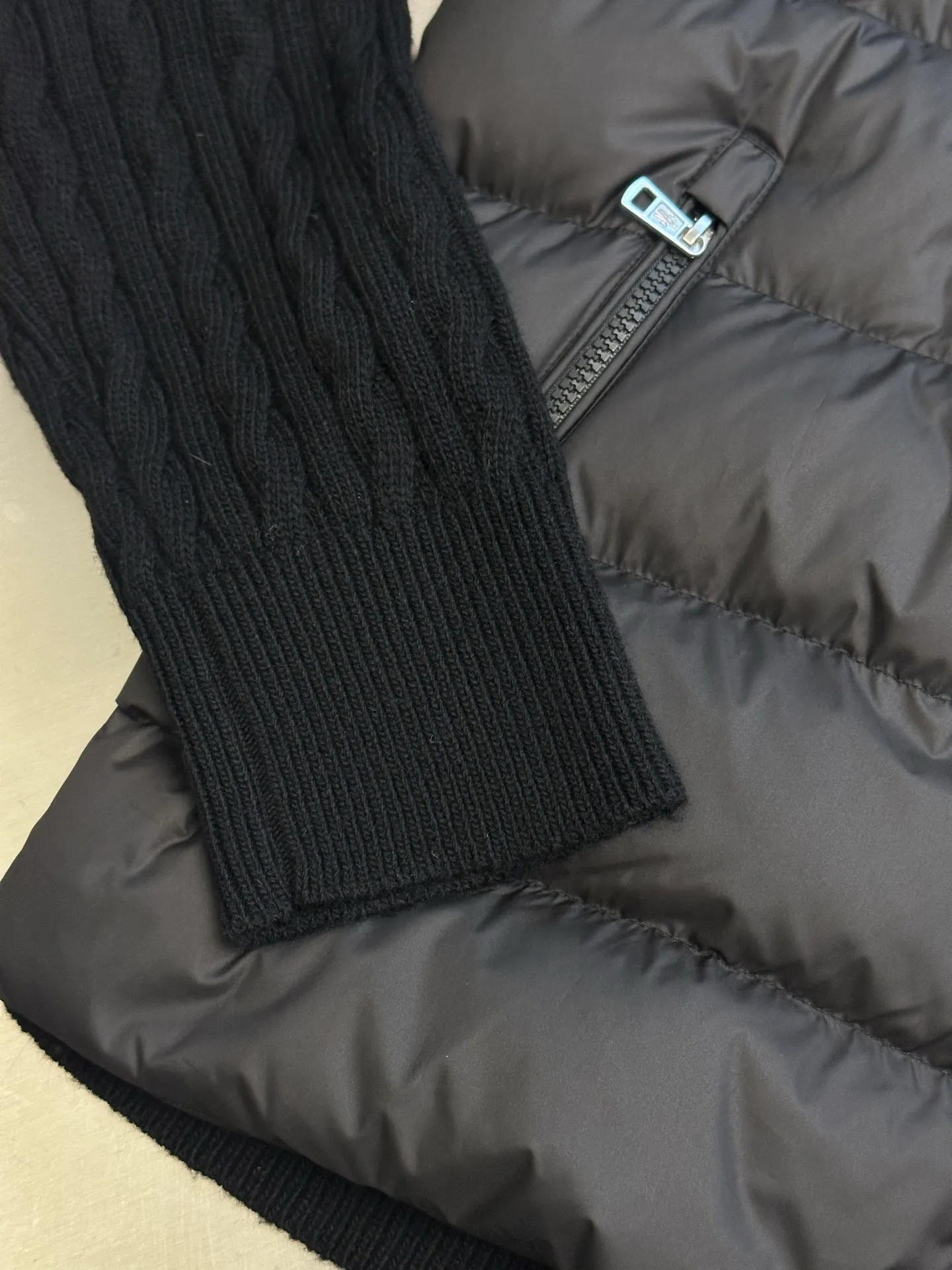 P770 Moncler Wool Spliced ​​Down Jacket The outer front fabric is made of 100% nylon (nylon). Its high-density structure achieves excellent windproof effect. It also has strong wear resistance and wrinkle resistance. It is scratch-free for daily wear and can be easily taken care of. The splicing design of sweaters and down jackets not only retains the thermal performance of down jackets, but also incorporates the fashion elements of sweaters, making the overall garment both practical and fashionable.  Filled with high-quality white duck down, with a filling capacity of 100g, it has excellent thermal insulation effect. At the same time, the sweater is made of wool, cashmere and other natural fibers, which are soft, comfortable and skin-friendly. The sweaters and down jackets are carefully spliced ​​to ensure comfortable wearing and are not prone to threading or velvet loss.  The high collar design not only provides excellent thermal insulation effect, but also adds a unique sense of fashion, allowing the wearer to maintain style in the cold season. The stripes on the sleeve arms are like bright brush strokes, embellished on the dark gray down jacket, injecting vitality and movement into the overall look, making the clothing more eye-catching.  size: 1.2.3.4