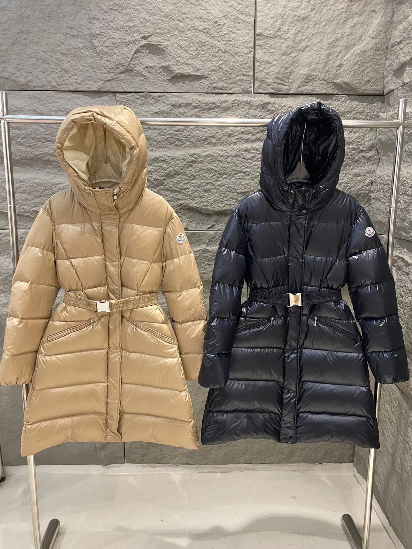P1060 Moncler's new Bellevue women's long belted down jacket. The Bellevue down jacket is made of iconic nylon laqué fabric, interpreting classic Moncler style. Long design, the fabric has been functionally treated for a gorgeous lustrous effect. This hooded thermal piece has a feminine silhouette and an elastic waistband. From day to night, from the city to the mountains, it can be easily handled. Color: Black/Camel Beige Size: 0/1/2/3