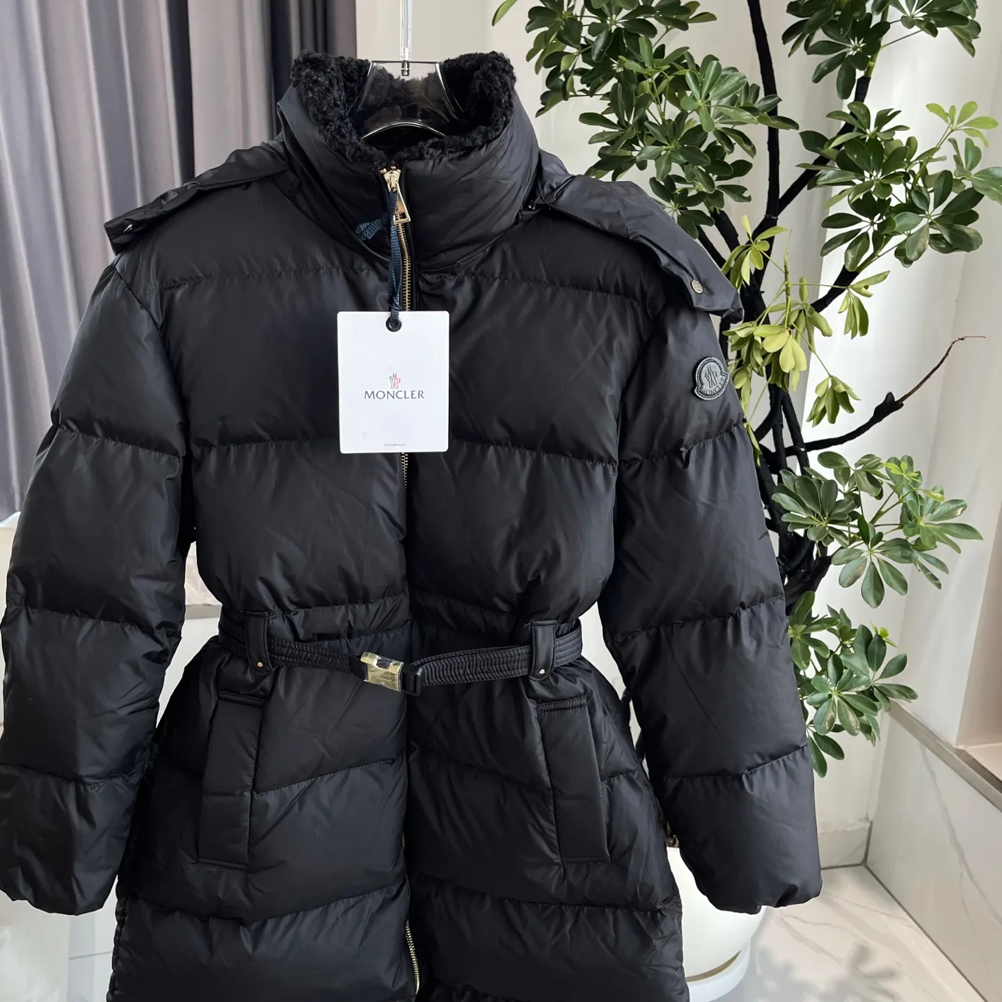 P1120 Moncler Briant Women's Hooded Long Waisted Down Jacket Jacket The Briant down jacket is designed to be both practical and comfortable to meet daily needs. Functional nylon fabric combined with a removable hood makes it easy to adapt to changing weather. This warm piece's wrap silhouette can be transformed from practical to sophisticated by adding a feminine touch with a detachable belt. The teddy velvet style collar design highlights the gentle style. Color: Black Size: 0/1/2/3