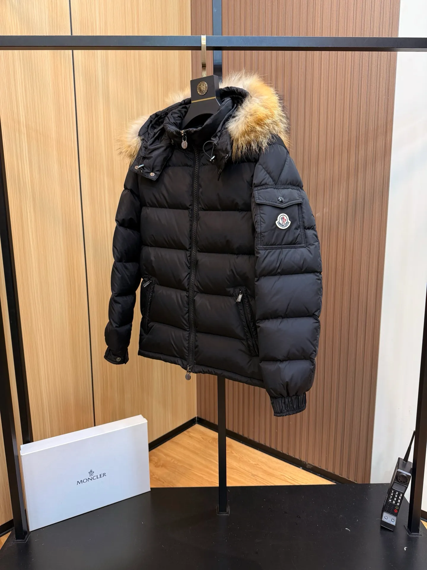 P1040 Moncler Mayaf short men's down jacket. The hood is removable. The fur collar is removable. Based on Maya, a removable fur collar is added. The Mayaf men's hooded down jacket is made of functional nylon fabric, and the hood is equipped with removable synthetic material trim.  The Mayaf short down jacket is a reinterpretation of the classic Moncler Maya style in an instantly recognizable silhouette, with a removable hood and adjustable hem. Made from functional fabric with removable synthetic trim on the hood. The sleeves are embellished with classic patch pockets, reflecting the brand's signature style. Details •Made from functional fabric •Technical fabric lining •Down-filled •Push-stud collar •Detachable hood with removable synthetic trim •Zip closure •Zip pockets •Patch pockets with press-stud •Adjustable elastic cuffs •Adjustable drawstring hem