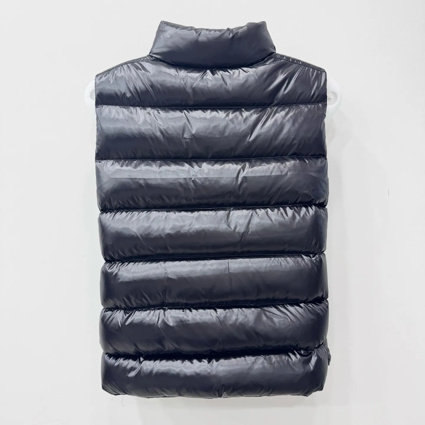 P560 Tibb men's down vest] Tibb men's down vest is a classic Moncler design item made of nylon laqué fabric.     The Tibb men's down vest is a classic Moncler item, inspired by the iconic archival silhouette of the 1980s. Made from lightweight nylon laqué functional fabric, it's perfect for changing seasons.  •Made of nylon laqué •Nylon laqué lining •Down filled •Snap-stud collar •Zip closure •Zip pockets •Fabric: 100% nylon; •Lining: 100% nylon; •Filling: goose down •Down content: 90%; except trim; •Size: 12345 Maximum wash temperature 30°C - Gentle wash; Do not bleach; Do not tumble dry; Ironing maximum temperature 110°C - without steam; Do not dry clean; Professional wet cleaning - Gentle wash; Lay flat to dry in shade; Wash separately; Recommend washing and ironing inside out