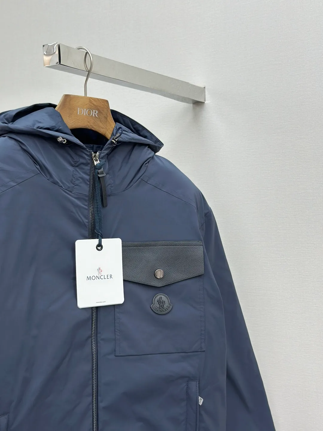 P890 MONCLER hooded jacket-style down jacket is made of 100% polyester fiber. After microfiberization treatment, the individual fibers become extremely fine, which greatly increases the fiber surface area, making the fabric soft and smooth, and the touch is close to natural fibers. The high-density textile method makes the structure tight, thus giving it a certain degree of wrinkle resistance, windproof warmth and wear resistance.  Lining selection: High-density lining fabric made of ultra-fine denier, 0.08mm thickness to avoid increasing the overall weight and making it smooth to wear. The high-density woven structure forms a wind resistance layer to protect the thermal efficiency of the thermal layer from loss. It can also withstand the expansion pressure of down and prevent deformation and damage after long-term use.  High-quality filling: 90 white duck down is selected, with a weight of 200g, ensuring excellent thermal insulation performance. After strict screening and treatment, the velvet is not easy to be drilled, ensuring durability. Details: The leather flap pocket on the chest is matched with a pebbled leather flap + matte metal buckle. It is low-key and exudes nobility. The hidden adjustment rope gives a sense of sophistication when you raise your hand. The "ID card" is directly embedded on the black satin inner patch pocket! Silver snaps + red, white and blue webbing, low-key yet exuding a sense of luxury, both visually and tactilely smooth.  Accessories: one-to-one customized buttons, one-to-one customized hem drawstring buckle, one-to-one customized phoenix eyes, one-to-one customized zipper pendant SIZE: 1 2 3 4