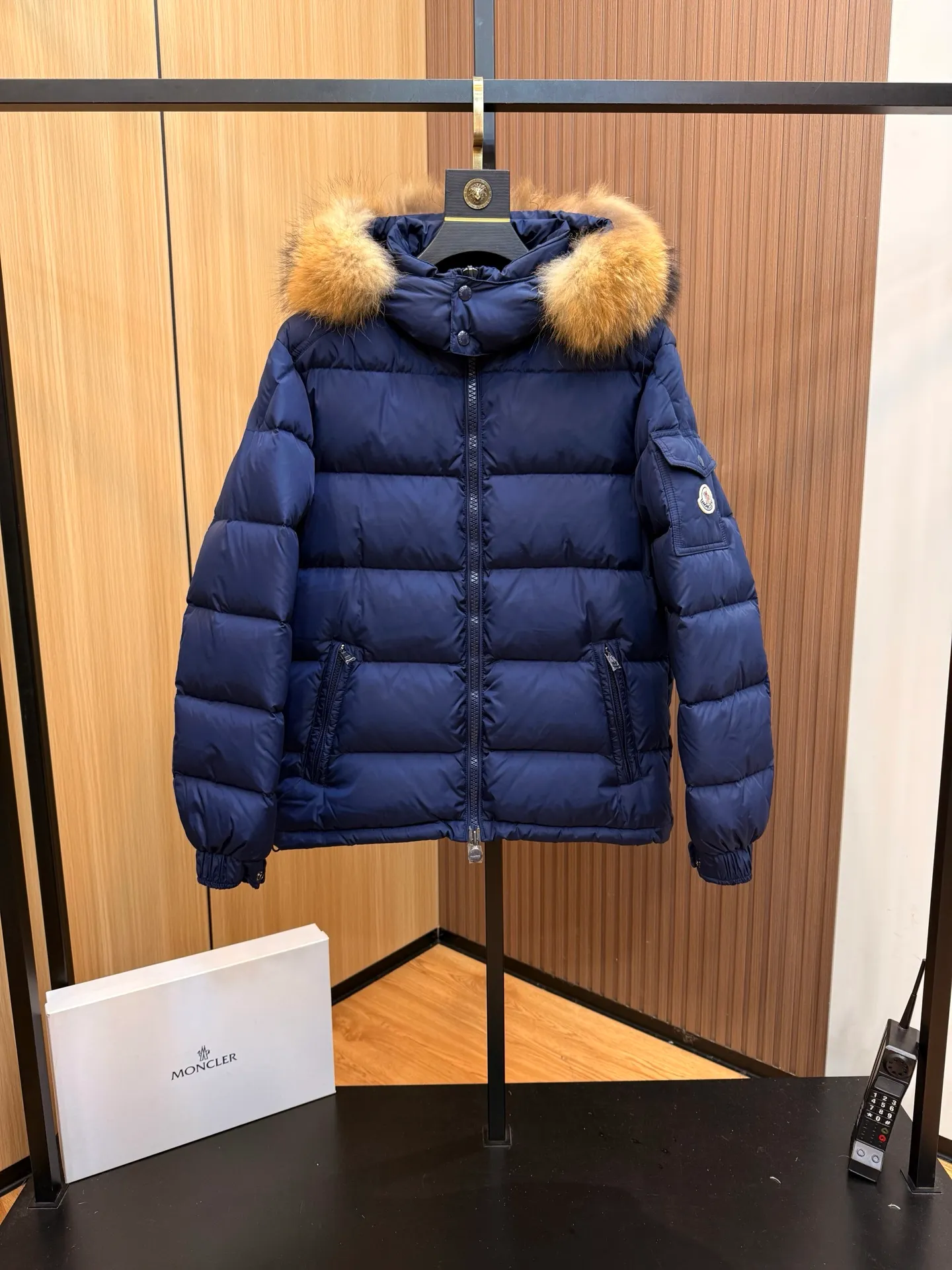 P1000 Moncler Mayaf short men's down jacket jacket. The hood is removable. The fur collar is removable. Based on Maya, a removable fur collar is added. The Mayaf men's hooded down jacket is made of functional nylon fabric, and the hood is equipped with removable synthetic material trim.  The Mayaf short down jacket is a reinterpretation of the classic Moncler Maya style in an instantly recognizable silhouette, with a removable hood and adjustable hem. Made from functional fabric with removable synthetic trim on the hood. The sleeves are embellished with classic patch pockets, reflecting the brand's signature style. Details •Made from functional fabric •Technical fabric lining •Down-filled •Push-stud collar •Detachable hood with removable synthetic trim •Zip closure •Zip pockets •Patch pockets with press-stud •Adjustable elastic cuffs •Adjustable drawstring hem