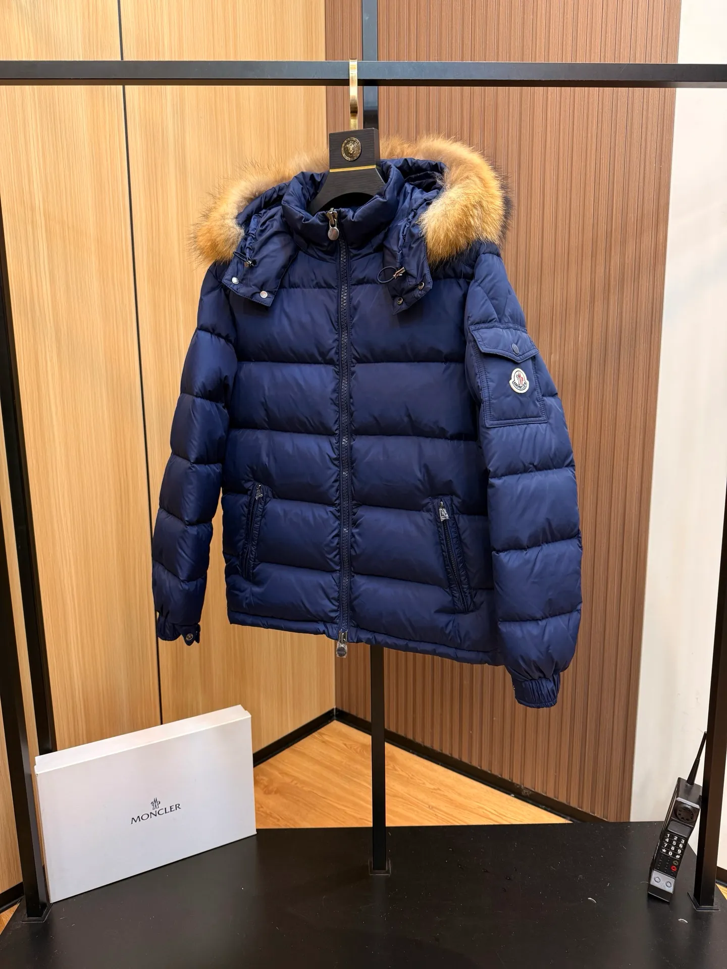 P1000 Moncler Mayaf short men's down jacket jacket. The hood is removable. The fur collar is removable. Based on Maya, a removable fur collar is added. The Mayaf men's hooded down jacket is made of functional nylon fabric, and the hood is equipped with removable synthetic material trim.  The Mayaf short down jacket is a reinterpretation of the classic Moncler Maya style in an instantly recognizable silhouette, with a removable hood and adjustable hem. Made from functional fabric with removable synthetic trim on the hood. The sleeves are embellished with classic patch pockets, reflecting the brand's signature style. Details •Made from functional fabric •Technical fabric lining •Down-filled •Push-stud collar •Detachable hood with removable synthetic trim •Zip closure •Zip pockets •Patch pockets with press-stud •Adjustable elastic cuffs •Adjustable drawstring hem