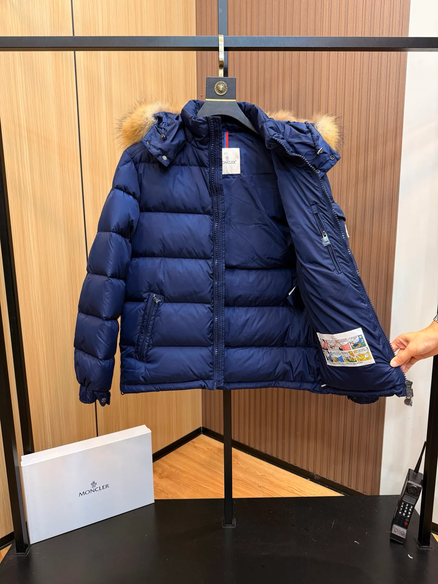 P1000 Moncler Mayaf short men's down jacket jacket. The hood is removable. The fur collar is removable. Based on Maya, a removable fur collar is added. The Mayaf men's hooded down jacket is made of functional nylon fabric, and the hood is equipped with removable synthetic material trim.  The Mayaf short down jacket is a reinterpretation of the classic Moncler Maya style in an instantly recognizable silhouette, with a removable hood and adjustable hem. Made from functional fabric with removable synthetic trim on the hood. The sleeves are embellished with classic patch pockets, reflecting the brand's signature style. Details •Made from functional fabric •Technical fabric lining •Down-filled •Push-stud collar •Detachable hood with removable synthetic trim •Zip closure •Zip pockets •Patch pockets with press-stud •Adjustable elastic cuffs •Adjustable drawstring hem