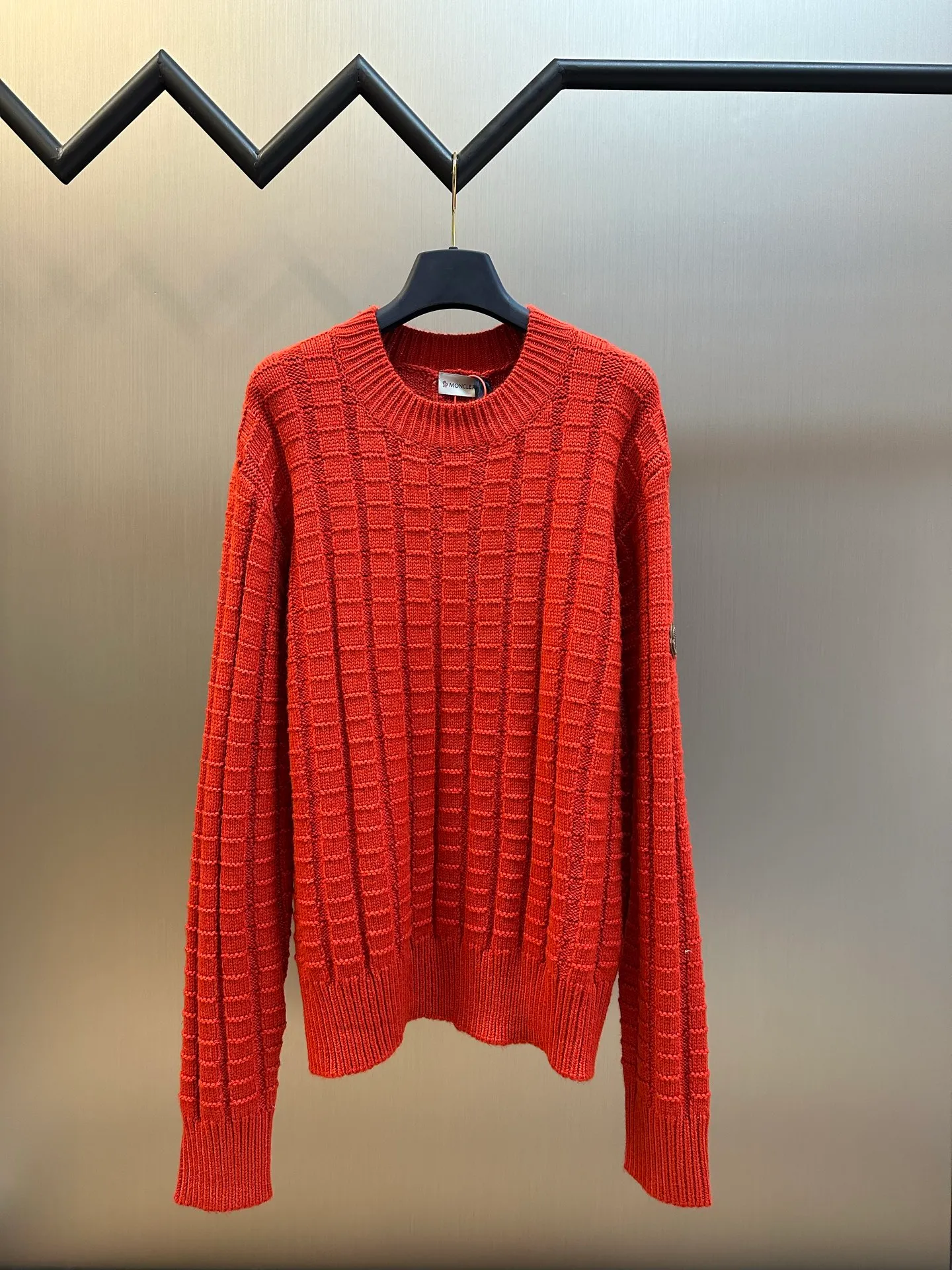 P430 Moncler embossed knitted logo sweater is made of custom-woven engraved wool texture, with three-dimensional texture as the brushstrokes. The entire embossed knitting reconstructs the dimension of knitted aesthetics. It produces a light and dark gradient texture halo as the human body moves. The iconic Moncler logo embroidered logo decorates the sleeves, making it highly recognizable.  The whole piece of embossed vertical grain knitting uses specific stitches and changes in fabric structure, and changes the arrangement of stitches and the density of the fabric, so that the vertical grains present a relief effect that is raised on the surface of the sweater, forming undulating changes in the vertical grains.  Curved thread structure, by changing the stitching method and the arrangement of yarns during the knitting process, makes the yarns present a curved distribution in the fabric.  size：s m l xl