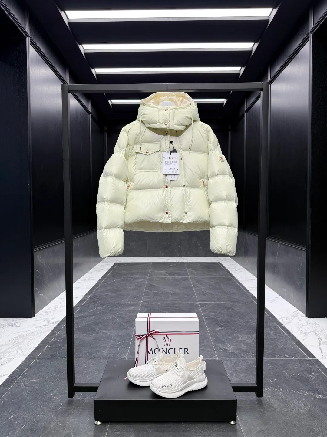 P900 Special down  The Erea down jacket is a modern take on shapes and textures. Short design in functional super laqué nylon with a glossy finish. This hooded insulated piece features a double-snap closure for an asymmetrical shape. The body and sleeves are quilted in varying sizes for a geometric feel. Details •Made from super laqué fabric •Nylon lining •Down filled •Removable and adjustable hood •Zip and snap closure •Zipper pockets •Snap fastening on chest pocket •Drawstring hem •Color Black/Cream White/Light Green Size: 0-2 Fairy Style D00730