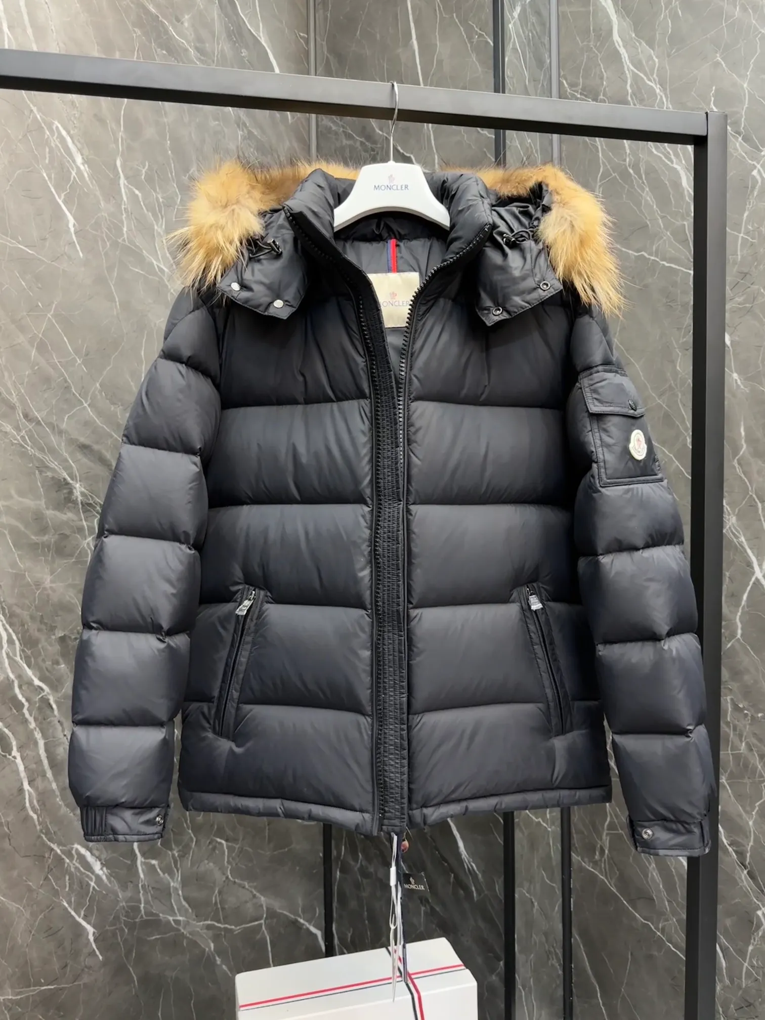 P1040 ⬆️Moncler Mayaf short men's down jacket. The hood is removable. The fur collar is removable. Based on Maya, a removable fur collar is added. The Mayaf men's hooded down jacket is made of functional nylon fabric, and the hood is equipped with removable synthetic material trim.  The Mayaf short down jacket is a reinterpretation of the classic Moncler Maya style in an instantly recognizable silhouette, with a removable hood and adjustable hem. Made from functional fabric with removable synthetic trim on the hood. The sleeves are embellished with classic patch pockets, reflecting the brand's signature style. Details •Made from functional fabric •Technical fabric lining •Down-filled •Push-stud collar •Detachable hood with removable synthetic trim •Zip closure •Zip pockets •Patch pockets with press-stud •Adjustable elastic cuffs •Adjustable drawstring hem