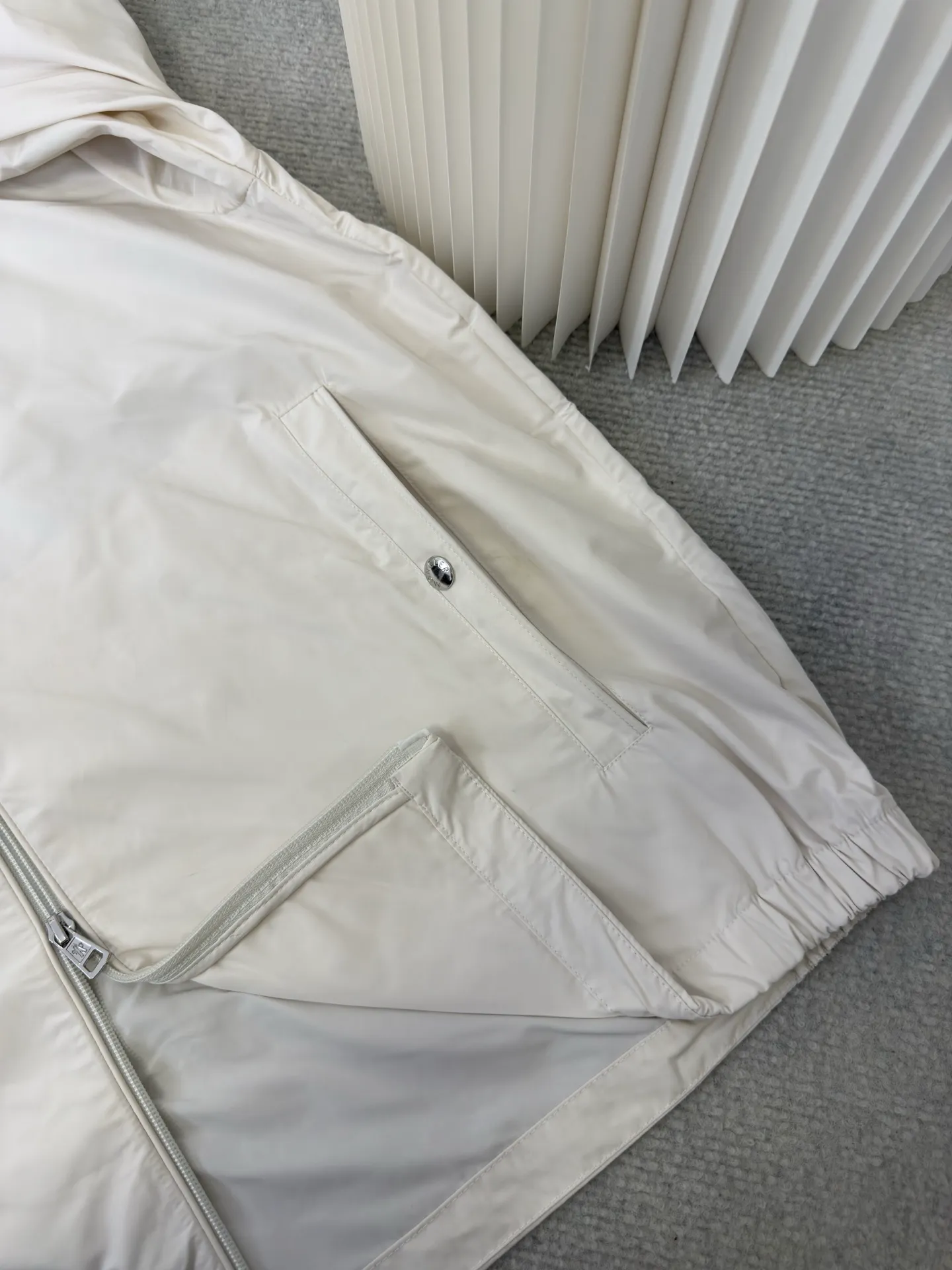 P570 MONCLER lightweight jacket with web trim at the mouth is made of 100% polyester fiber to create a tough protective outer layer. It is famous for its excellent tear resistance and wear resistance. It can quickly return to flatness during wearing and maintain the crisp and stylish appearance of the clothing for a long time. At the same time, it is not easy to deform after being washed for a long time.  Decorative edging in two different colors has been added to the center section of the sleeves. This design element not only adds visual highlights to clothing, making it more fashionable and unique. The webbing is precisely positioned along the cuffs to the seam of the collar and hat to ensure symmetry and overall smoothness. Before actual sewing, use very fine basting stitches for pre-fixing. This step is crucial to prevent the webbing from slipping, twisting, or wrinkling during sewing and ensuring that the final stitch is straight and perfect. Size 1 2 3 4