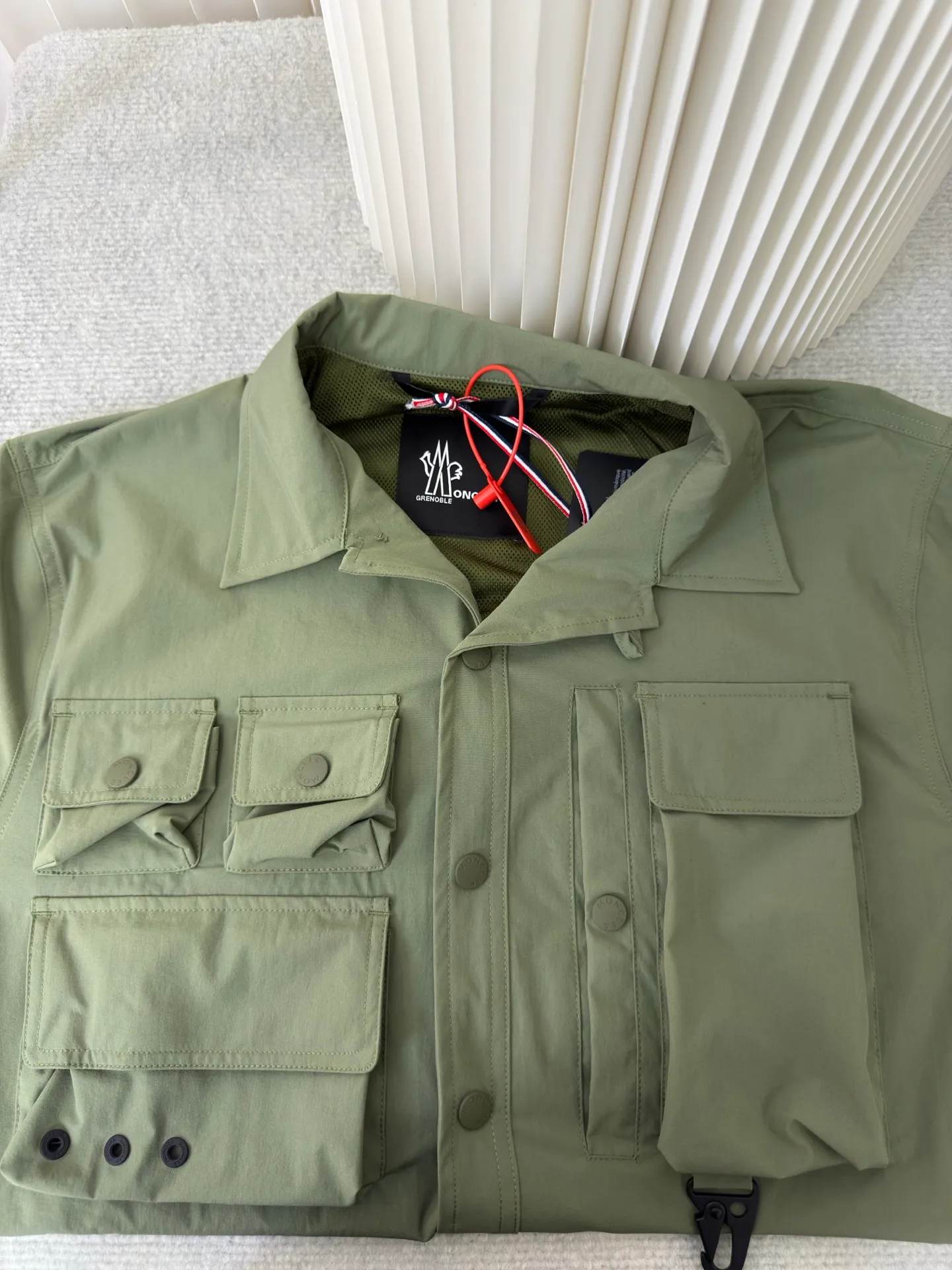 P640 Moncler Grenoble Functional Outdoor Jacket Custom-dyed double-stretch mercerized poplin Custom-dyed soft-mesh pongee Excellent texture Comfortable and close to the skin Dark green inspired by plant texture The color is taken from sage leaves soaked in morning dew Precision narrative of functional pocket system Balance of function and aesthetics The iconic Moncler logo appears on the sleeves, fully recognizable The triangular logo of the same color is hidden in the fabric texture like a mark in the undercurrent of the deep sea Extremely hidden and visible. The detachable sleeve design allows for diversified outfits. You can switch styles at will. Feel free and elegant. Show your dignity. Balance outdoor practicality and urban aesthetics. Lead the fashion. Adopt three-in-one process. Give priority to evenly coating the glue on the surface of the substrate that needs to be composited. Then dry and solidify. Then laminate the substrate with the adhesive film and the non-woven fabric. Then cool and solidify. Then composite the filter non-woven fabric. The workmanship is cumbersome and complex. Time-consuming and labor-intensive. Embossed composite technology Through computer scanning, ensure that the imprint size and shape are consistent with the original. Then use special glue as an adhesive to combine and then solidify to achieve complete dryness and the best bonding effect. Use CNC laser burning and cutting based on the high-energy characteristics of the laser. Precisely control the movement path of the laser beam with a laser generator to achieve precise cutting of the shape of the piece. Template machine bag opening. The preset template guides the position, shape and size of the bag opening. The accuracy ensures the quality of the bag opening effect. Uses infrared special machine to fasten the position more accurately. Strong and sturdy, loose fit, detachable sleeve splicing, style can be switched at will Size: 1 2 3 4