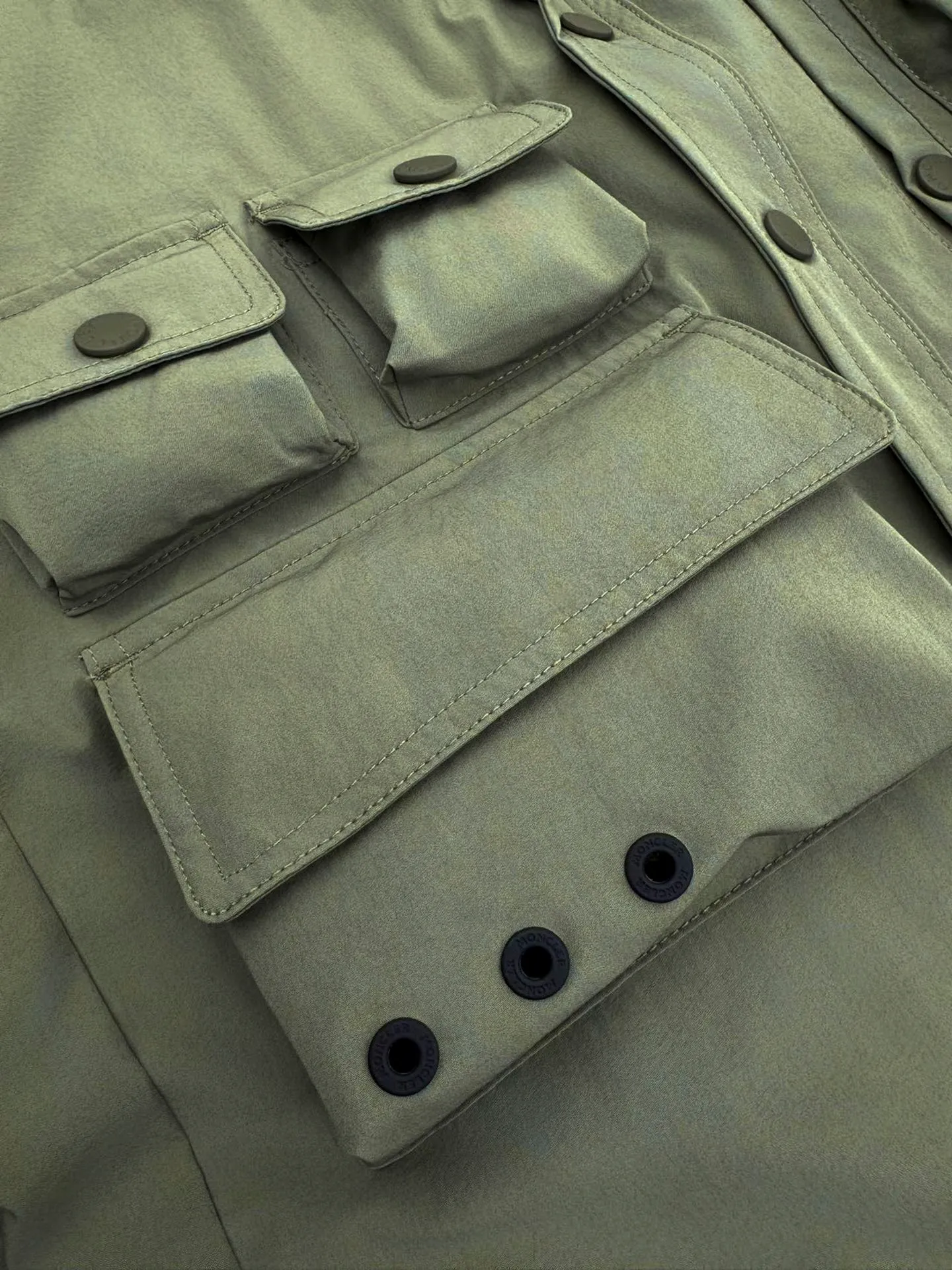 P610 Moncler Grenoble functional outdoor jacket Custom-dyed double-stretch mercerized poplin Custom-dyed soft mesh pongee Excellent texture Comfortable and close to the skin Dark green inspired by plant texture The color is taken from sage leaves soaked in morning dew Precision narrative of functional pocket system Balance of function and aesthetics The iconic Moncler logo appears on the sleeves for full recognition The triangular logo of the same color is hidden in the fabric texture like a mark in the undercurrent of the deep sea, extremely invisible and yet obvious The detachable sleeve design allows for diversified outfits. You can switch styles at will. It is chic and free, showing nobility. It balances outdoor practicality and urban aesthetics and leads the fashion. Process 1: Adopt a three-in-one process. Prioritize and evenly coat the glue on the surface of the substrate that needs to be composited, and then dry and solidify it. Then laminate the substrate with the adhesive film and the non-woven fabric, then cool and solidify, and then composite it with the filter non-woven fabric. The workmanship is cumbersome and complex, time-consuming and labor-intensive. Process 2: Embossing composite technology uses computer scanning to ensure that the imprint size and shape are consistent with the original, and then uses special glue as an adhesive to combine and solidify to achieve complete dryness and the best bonding effect. Process 3: Use CNC laser burning and cutting. Based on the high-energy characteristics of the laser, the moving path of the laser beam is precisely controlled by the laser generator to achieve precise cutting of the shape of the piece. Process 4: Template machine bag opening. The preset template guides the position, shape and size of the bag opening. The accuracy ensures the quality of the bag opening effect. Process 5: Using infrared special machine buttoning, the position is more precise and strong. Accessories: Customized 1:1 Moncler snap button Customized 1:1 Moncler resin buckle Customized 1:1 Moncler logo seal Customized 1:1 Moncler logo armband Customized 1:1 Moncler zipper rope ring Customized 1:1 Moncler zipper pull Customized 1:1 Moncler trademark Version: Loose version Function: Detachable sleeve splicing Style can be switched at will Size: 1 2 3 4