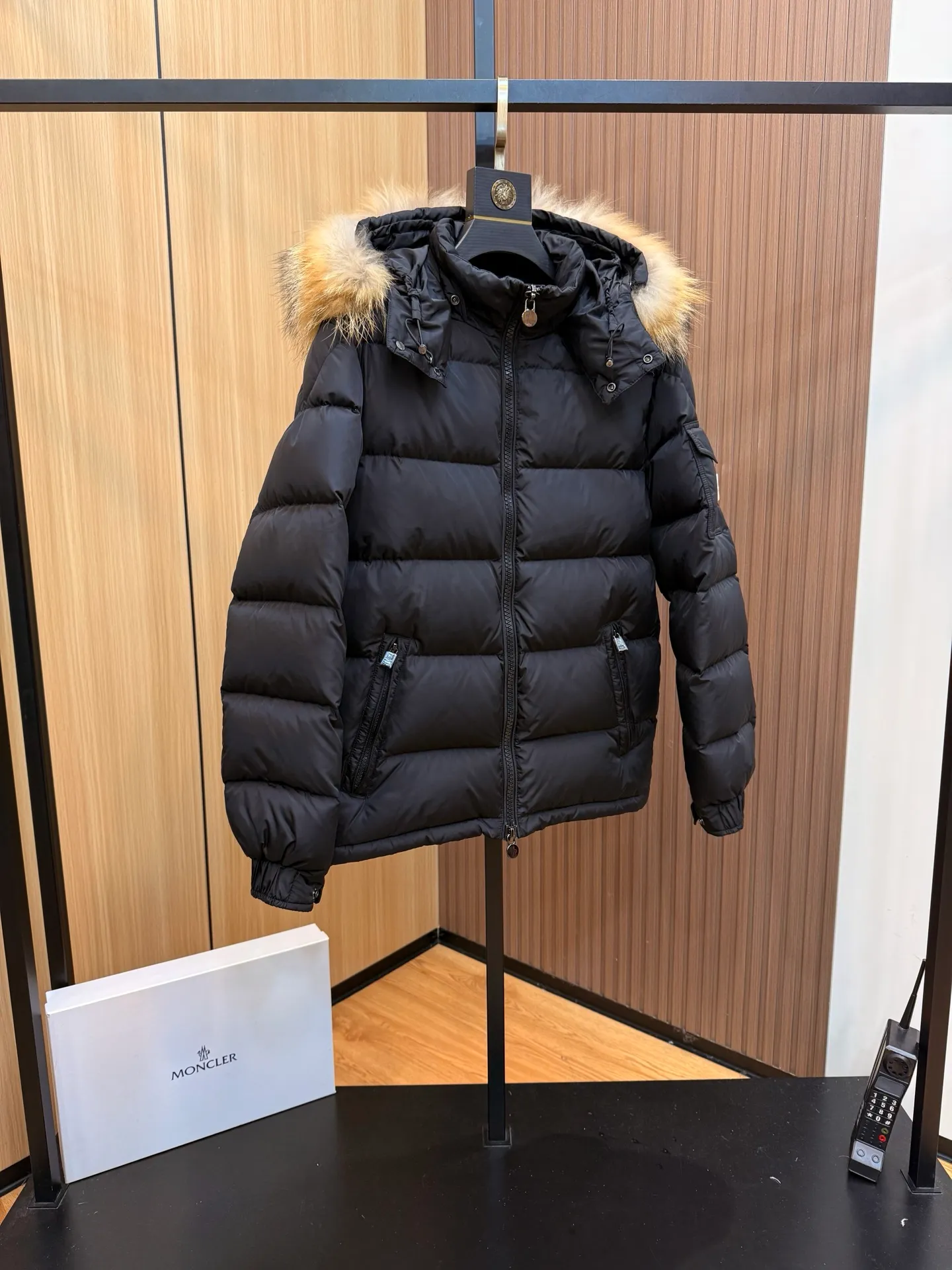 P1000 Moncler Mayaf short men's down jacket jacket. The hood is removable. The fur collar is removable. Based on Maya, a removable fur collar is added. The Mayaf men's hooded down jacket is made of functional nylon fabric, and the hood is equipped with removable synthetic material trim.  The Mayaf short down jacket is a reinterpretation of the classic Moncler Maya style in an instantly recognizable silhouette, with a removable hood and adjustable hem. Made from functional fabric with removable synthetic trim on the hood. The sleeves are embellished with classic patch pockets, reflecting the brand's signature style. Details •Made from functional fabric •Technical fabric lining •Down-filled •Push-stud collar •Detachable hood with removable synthetic trim •Zip closure •Zip pockets •Patch pockets with press-stud •Adjustable elastic cuffs •Adjustable drawstring hem