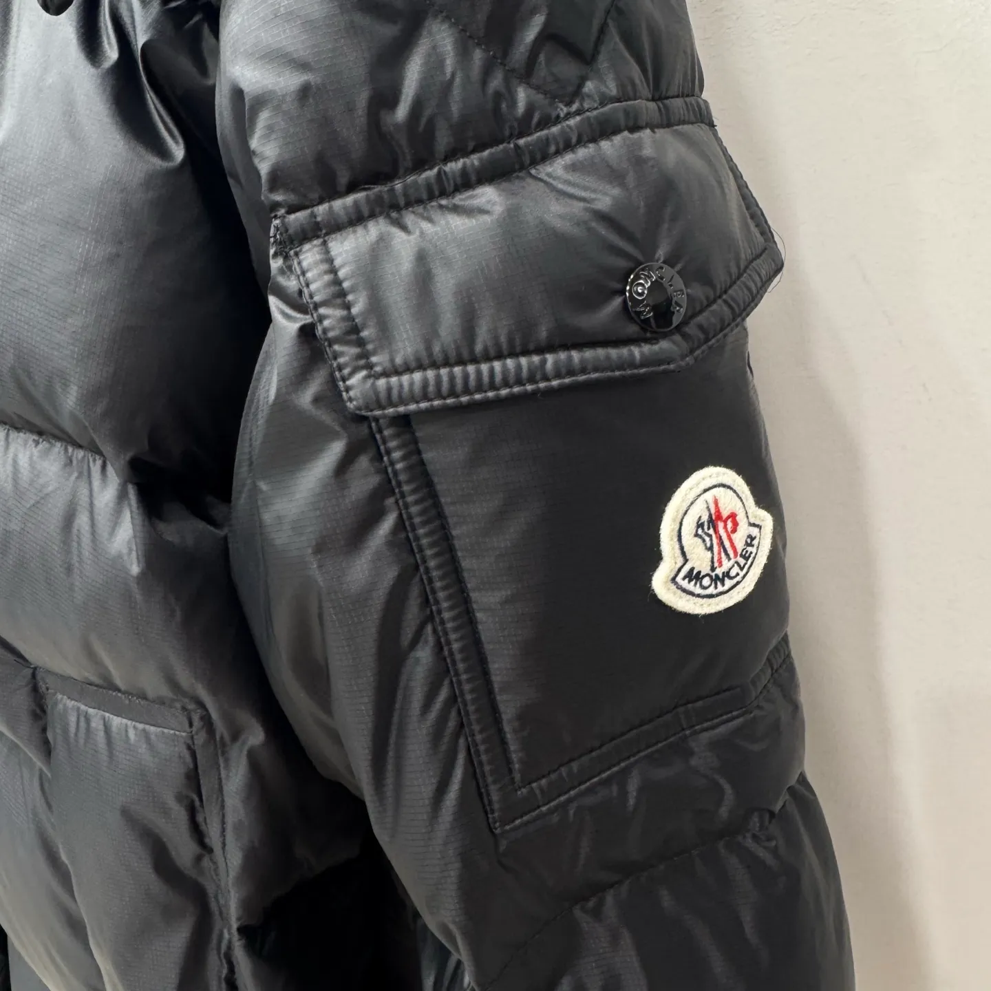 P1100 Brand: Moncler Filling: 90 white duck down Weight: 380-450 Color: White Black Gray Size: 12345 [Couyere Men's Hooded Short Down Jacket] The Couyere short down jacket is durable and practical, provides functional warmth and care, and will accompany you to meet challenges.  The Couyere is a durable down jacket made from a fine fabric that's durable and functional, with velvet resistance and functionality. The short design creates a sculpted silhouette, and padded pockets add a modern feel. The sleeves are embellished with signature patch pockets, a nod to the classic Moncler Maya down jacket.  • Made of fine ripstop fabric • Fine fabric lining • Down filling • Detachable and adjustable hood • Zip closure • Zippered pockets • Press-studs on sleeve pockets • Elastic cuffs • Drawstring hem Fabric: 100% nylon; Lining: 100% nylon; Filling: Goose down Down content: 90%; except upholstery; Maximum wash temperature 30°C - Mild wash; Do not bleach; Do not tumble dry; Ironing maximum temperature 110°C - without steam; Hydrocarbon dry cleaning - gentle wash; Professional wet cleaning - gentle wash; Lay flat to dry in shade; Wash separately; Remove removable accessories before washing; Recommend washing and ironing inside out