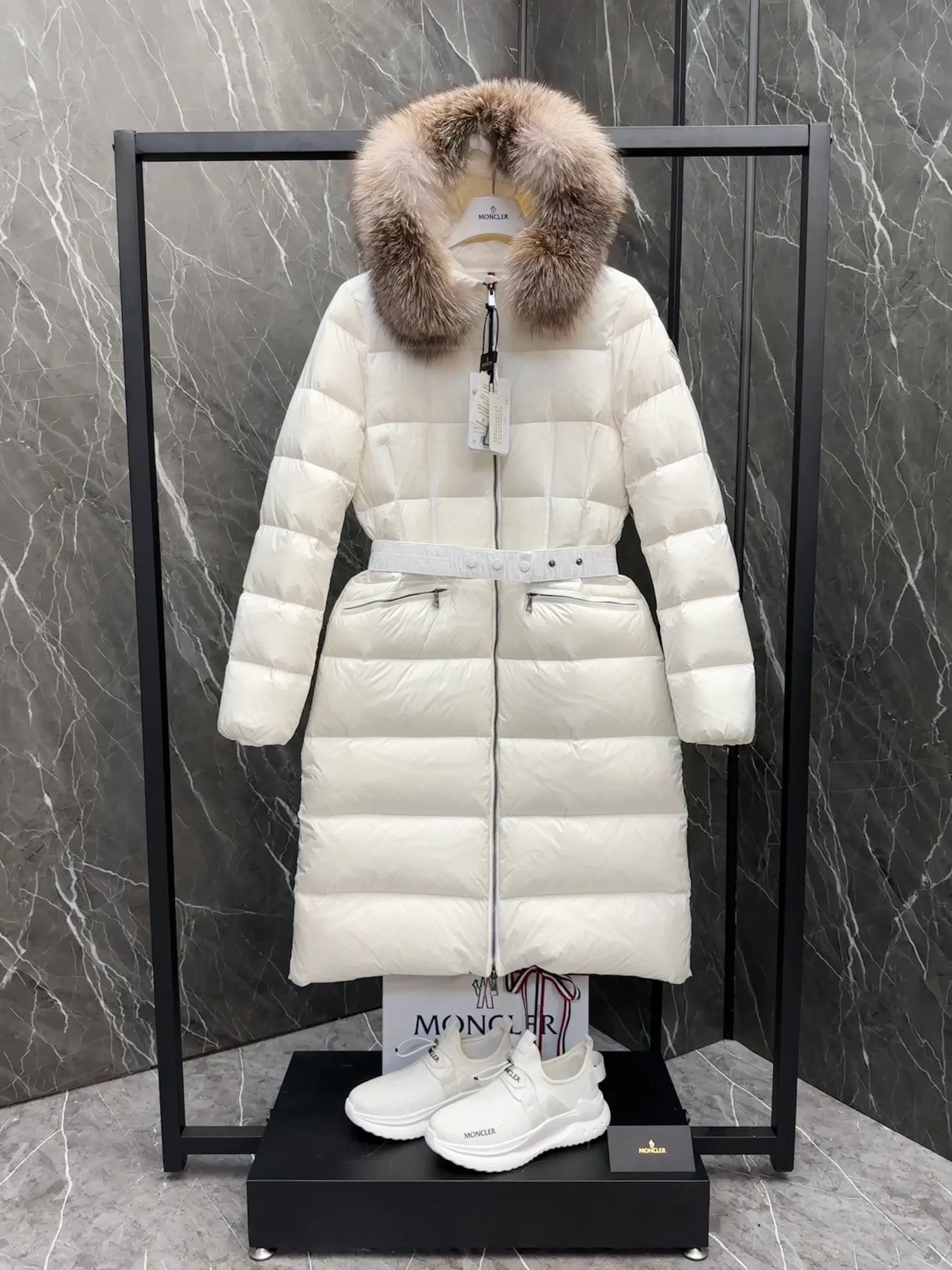 P1020 Moncler Boedic long down jacket for women. (Classic fox fur collar) adopts a whole fox fur collar imported from Finland. The Boedic long down jacket combines exquisite materials and attention to details. The timeless and elegant fashion design can provide you with a warm and caring wearing experience.  Boedic's long down jacket features a waist-cinching belt to accentuate its feminine silhouette for a stylish winter look. The cozy hood has rich fleece trim and is easily removable to suit your mood and weather conditions. Details •Made from lounge saison fabric •Longue saison lining •Filled with down •Hood with removable fox fur collar trim •Two-way zip closure •Elastic waistband with snap button closure •Zip pockets with grosgrain detail •Elastic cuffs Size : 1-4