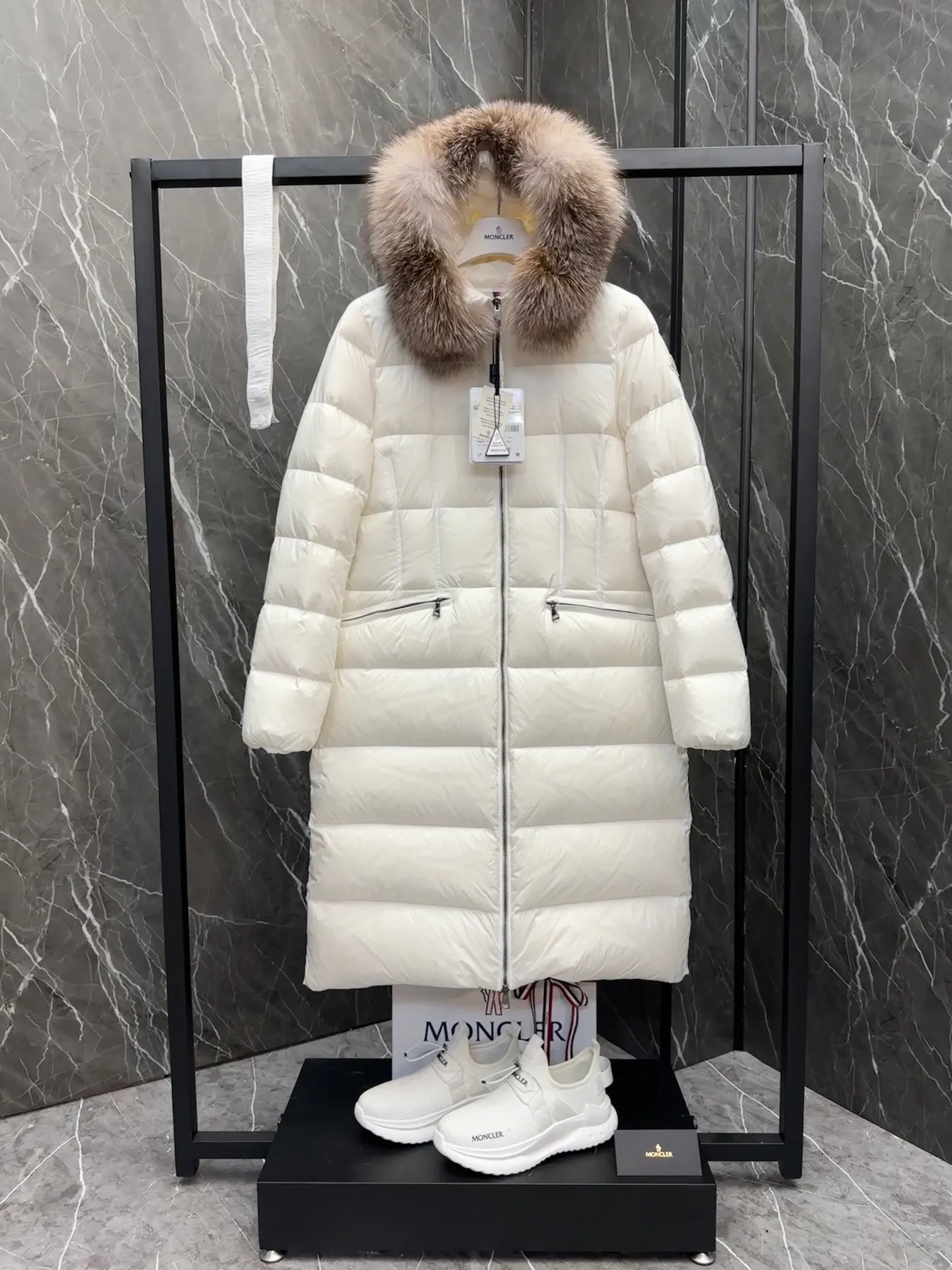 P1020 Moncler Boedic long down jacket for women. (Classic fox fur collar) adopts a whole fox fur collar imported from Finland. The Boedic long down jacket combines exquisite materials and attention to details. The timeless and elegant fashion design can provide you with a warm and caring wearing experience.  Boedic's long down jacket features a waist-cinching belt to accentuate its feminine silhouette for a stylish winter look. The cozy hood has rich fleece trim and is easily removable to suit your mood and weather conditions. Details •Made from lounge saison fabric •Longue saison lining •Filled with down •Hood with removable fox fur collar trim •Two-way zip closure •Elastic waistband with snap button closure •Zip pockets with grosgrain detail •Elastic cuffs Size : 1-4