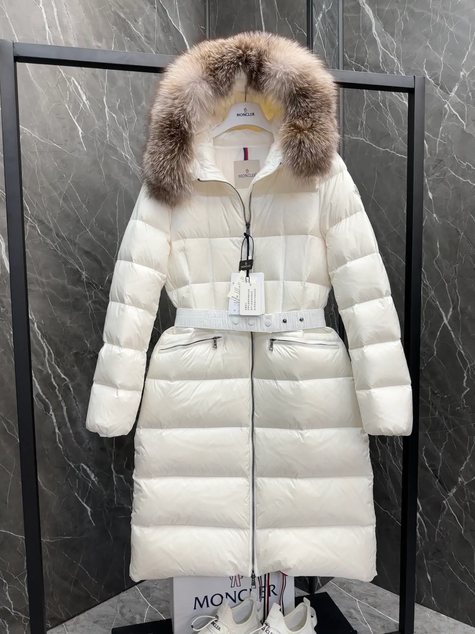 P1020 Moncler Boedic long down jacket for women. (Classic fox fur collar) adopts a whole fox fur collar imported from Finland. The Boedic long down jacket combines exquisite materials and attention to details. The timeless and elegant fashion design can provide you with a warm and caring wearing experience.  Boedic's long down jacket features a waist-cinching belt to accentuate its feminine silhouette for a stylish winter look. The cozy hood has rich fleece trim and is easily removable to suit your mood and weather conditions. Details •Made from lounge saison fabric •Longue saison lining •Filled with down •Hood with removable fox fur collar trim •Two-way zip closure •Elastic waistband with snap button closure •Zip pockets with grosgrain detail •Elastic cuffs Size : 1-4